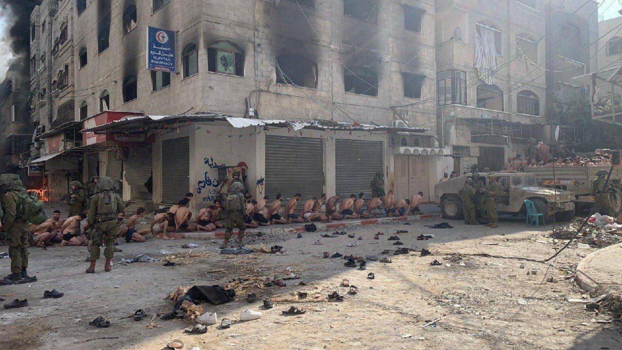 Detained Palestinians on a street in Beit Lahia, northern Gaza Strip, as Israeli soldiers stand guard. Photo: Reuters