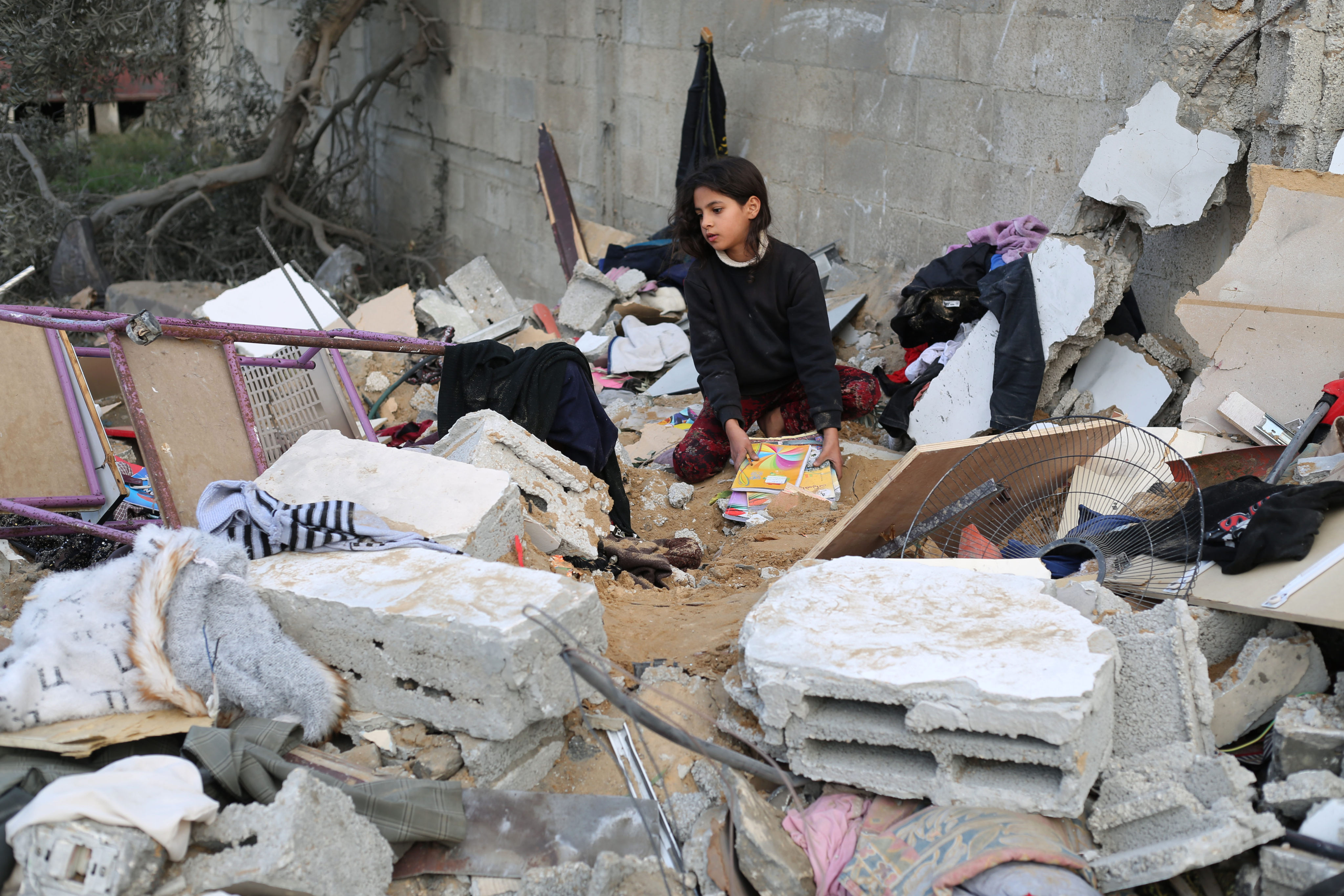 A girl collects items among the rubble of a building after an Israeli airstrike in the southern Gaza Strip city of Rafah on December 12.  Photo: Xinhua