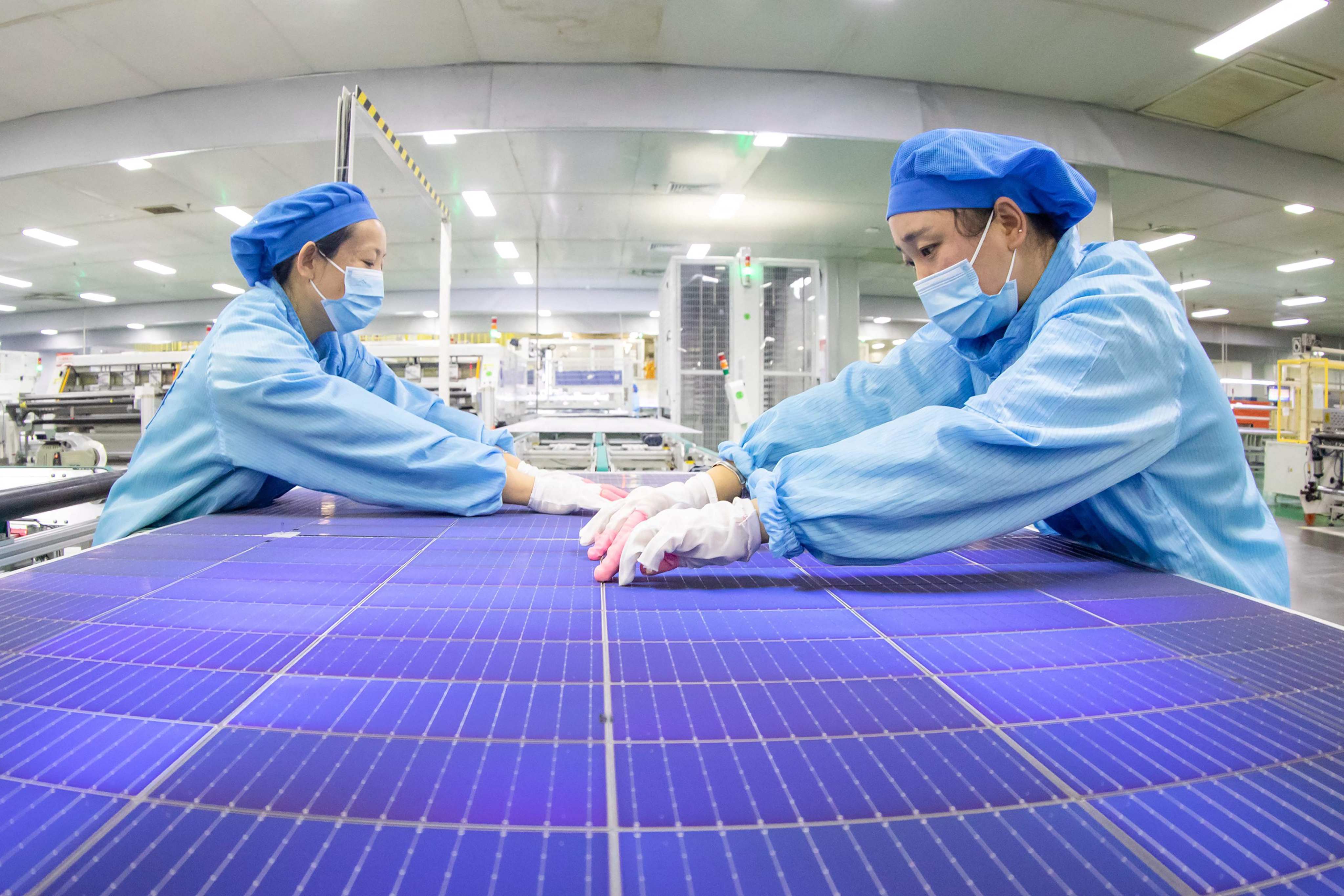 Employees work on solar photovoltaic modules at a factory in China’s Jiangsu province last month. Much of the power generated by solar panels scattered across residents’ rooftops currently cannot be transmitted to a power grid. Photo: AFP