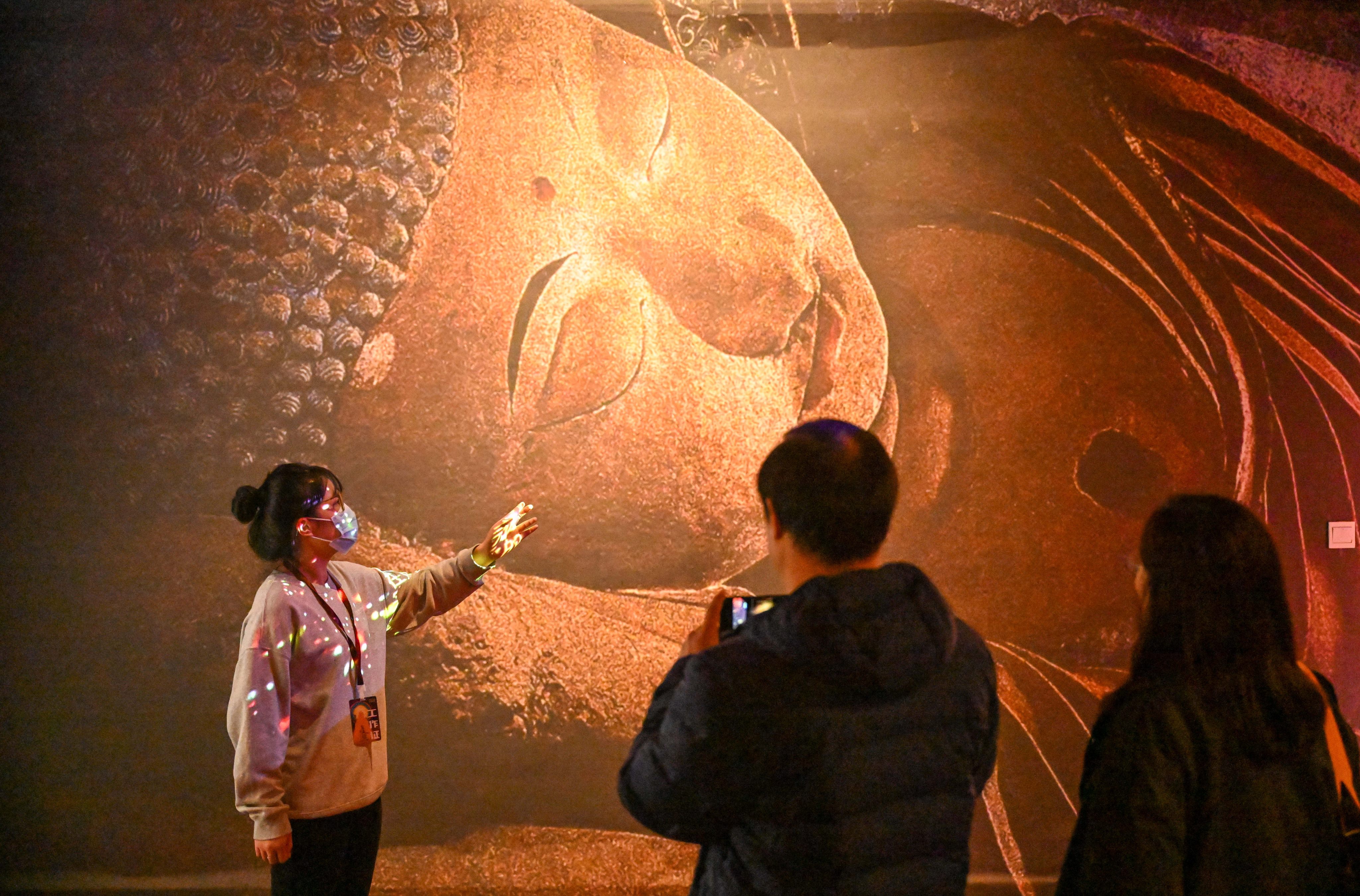 A guide introduces a work at an exhibition on Dunhuang culture at the Tianjin Digital Art Museum in Tianjin on November 28. In recent years, China has seen significant climate-related damage to its cultural heritage sites, including the Dunhuang caves. Photo: Xinhua 