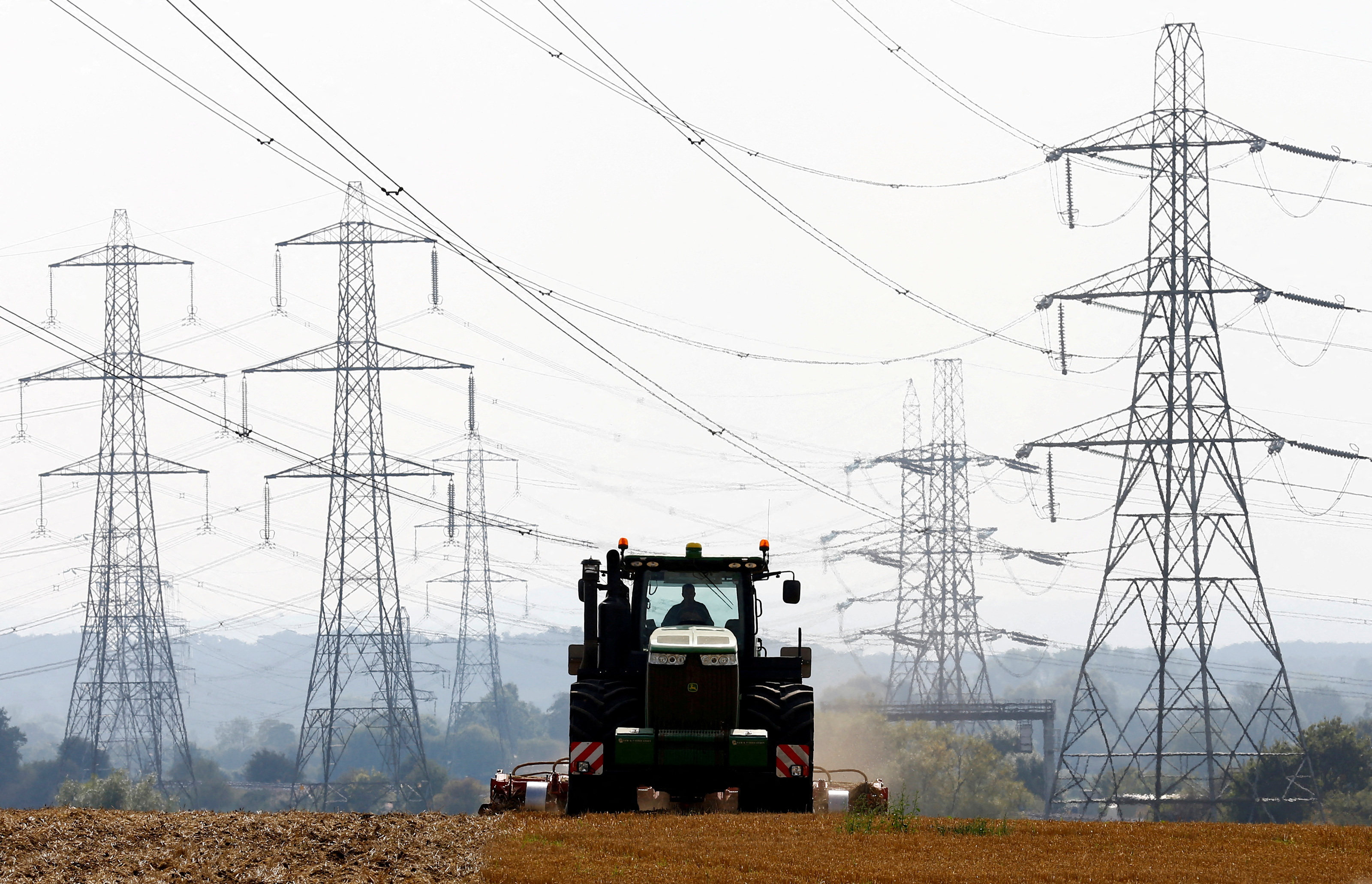 A farmer works in a field surrounded by electricity pylons in Ratcliffe-on-Soar, central England. Photo: Reuters