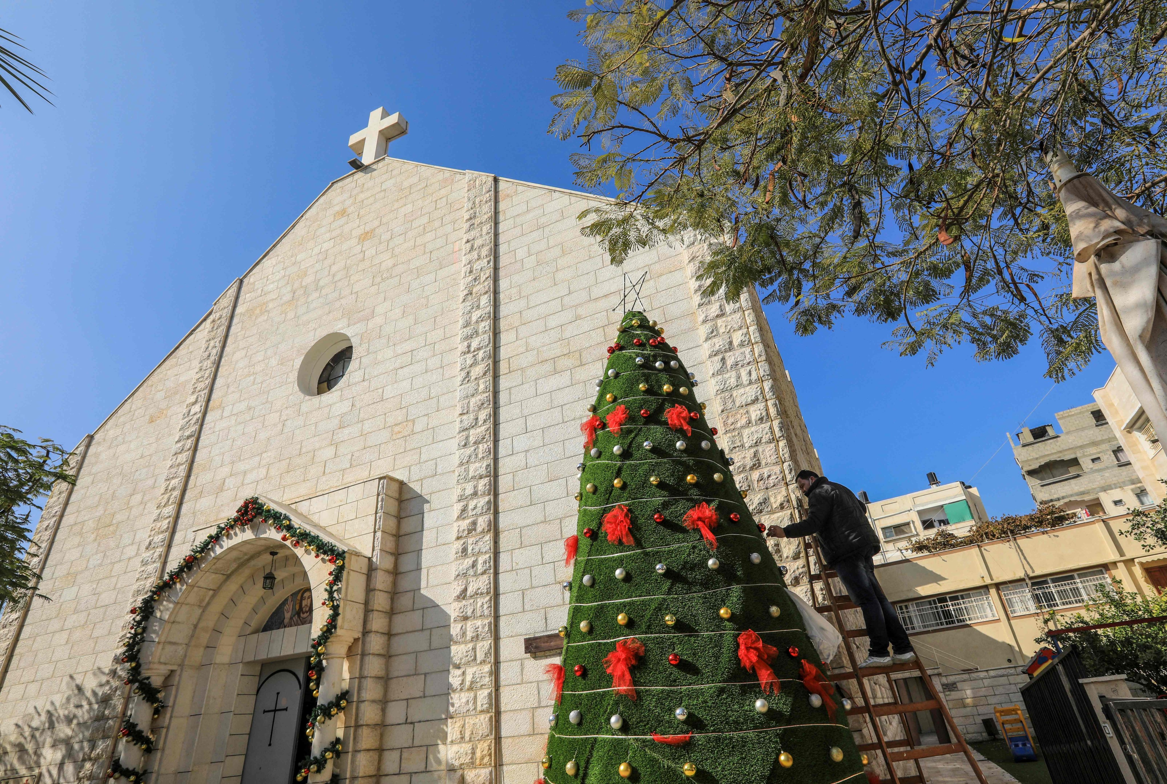 A man decorates a Christmas tree outside the Roman Catholic Church of the Holy Family in Gaza City in December 2020. Photo: AFP