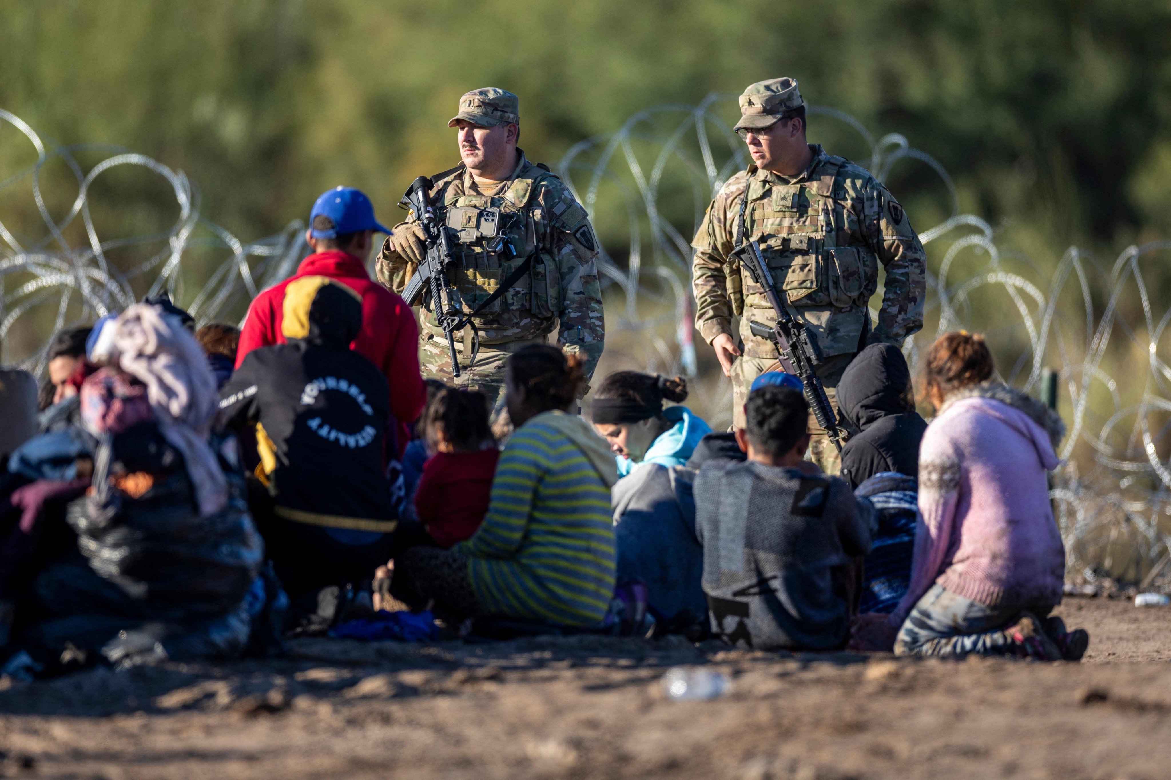Texas National Guard troops watch over some of more than 1,000 migrants who had crossed the Rio Grande overnight from Mexico on Monday in Eagle Pass, Texas. Photo: Getty Images via AFP