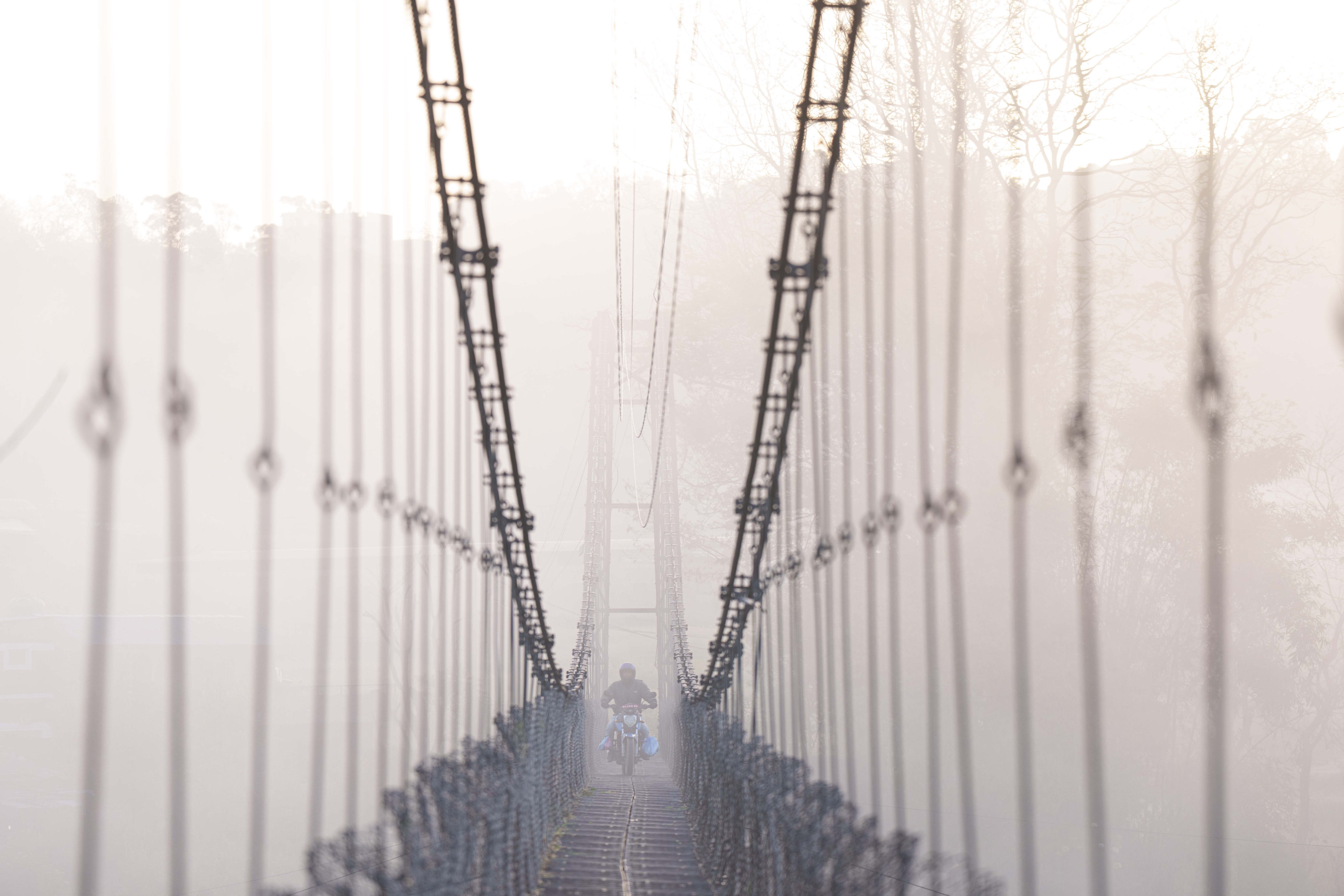 A man on a motorcycle crosses a suspension bridge over the Bagmati river in Lalitpur, Nepal, on March 27. Nepal has significant potential for generating surplus energy from hydropower  Photo: AP 