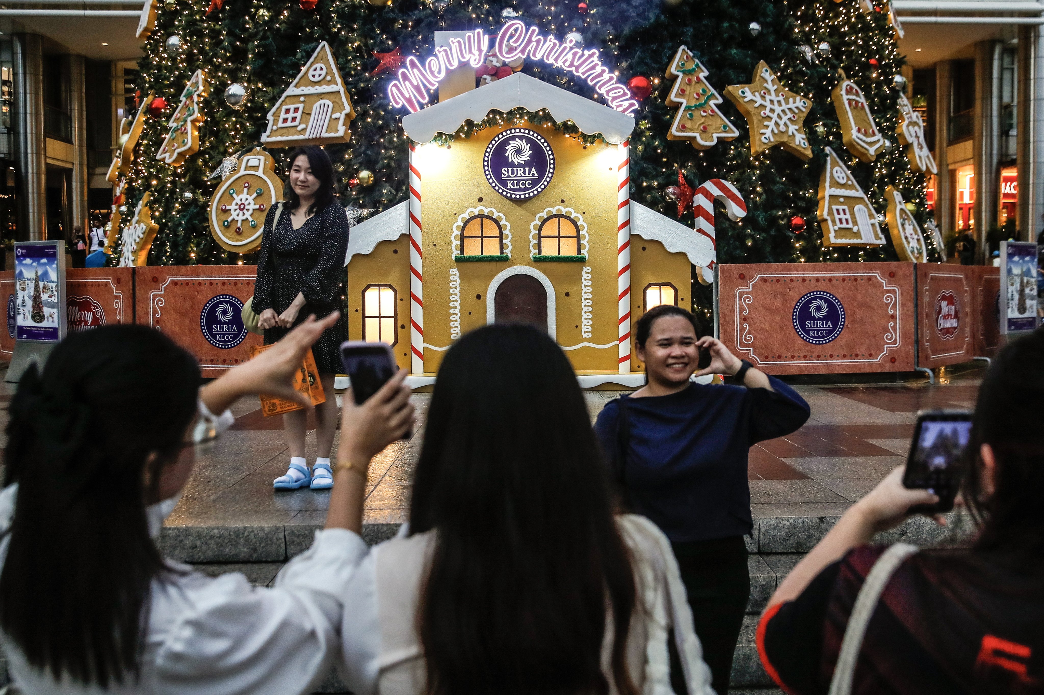 epa11015365 Women take pictures in front of the tallest Christmas tree replica in Malaysia standing at 32 meters in height at the Petronas Twin Towers in Kuala Lumpur, Malaysia, 07 December 2023. Christmas is celebrated in Malaysia and across the world on 25 December.  EPA-EFE/FAZRY ISMAIL