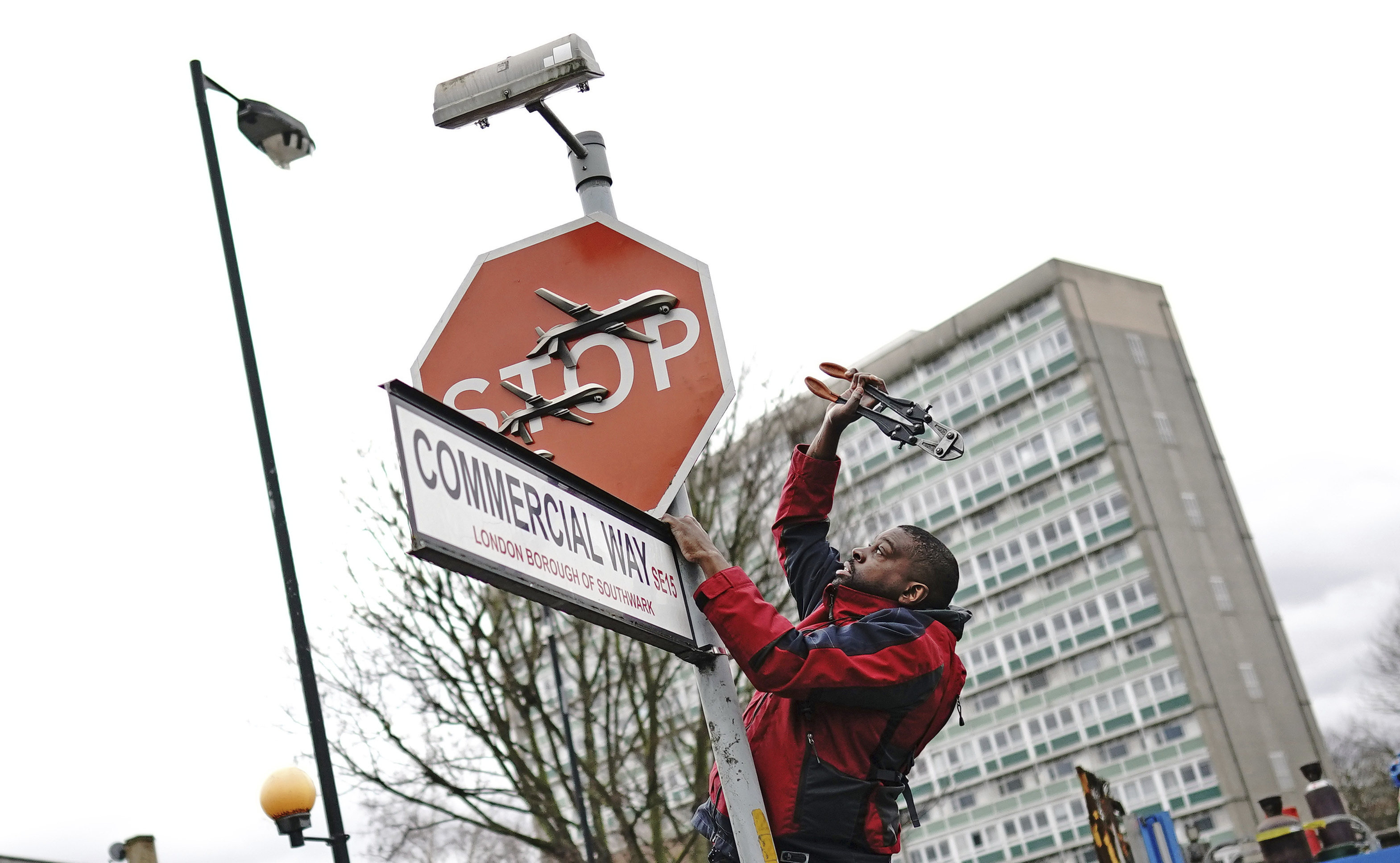 A man removes a piece of art by Banksy from an intersection in London on Friday. Photo: PA via AP