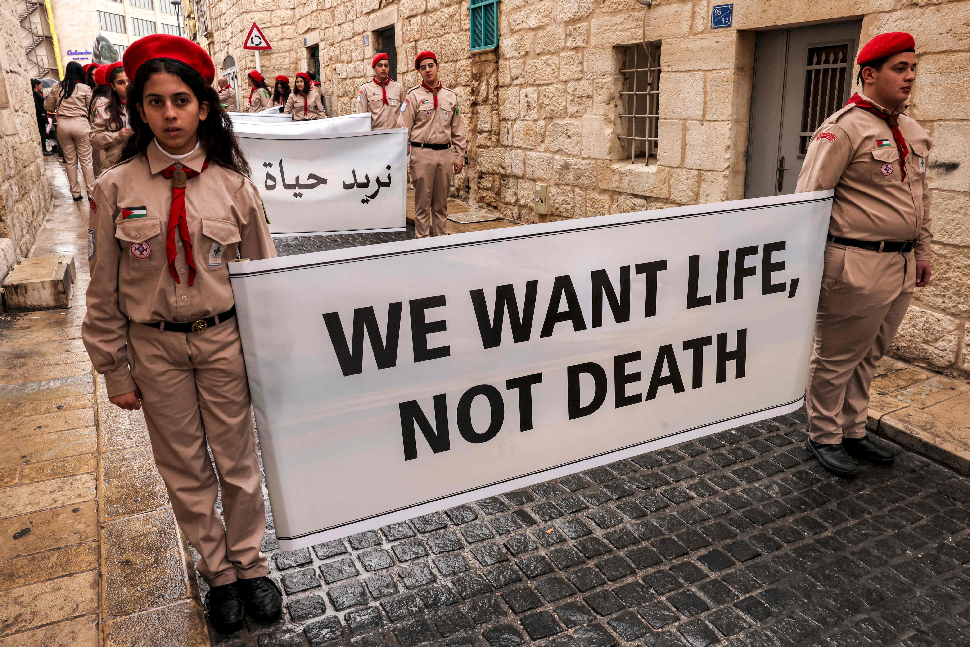 Palestinian youth members of the scouting movement hold up banners condemning and calling for an end of the conflict in the Gaza Strip between Israel and the Palestinian militant Hamas in the biblical city of Bethlehem. Photo: AFP