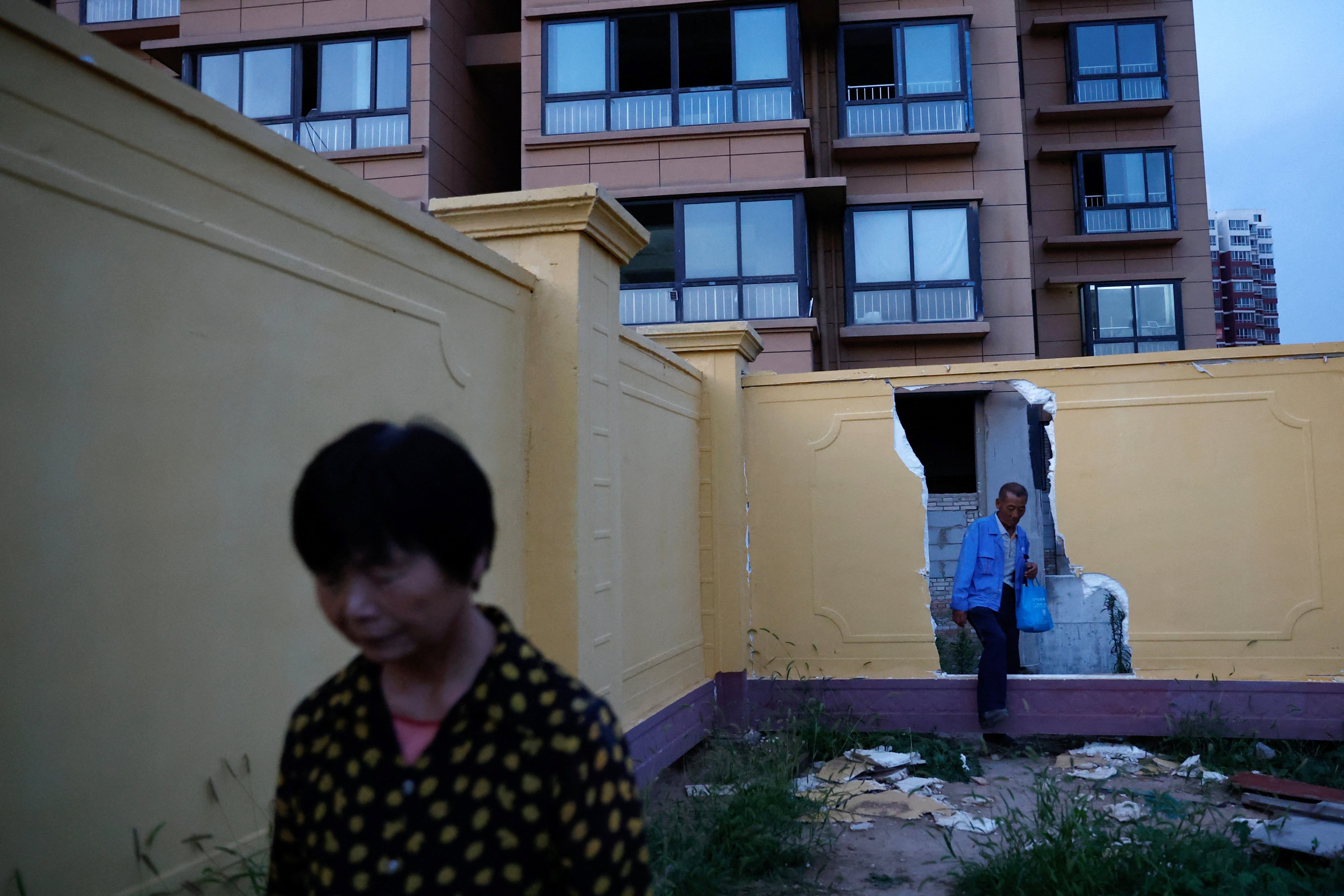 Homebuyers leave their residential compound through a hole in a wall, at the unfinished Gaotie Wellness City complex in Tongchuan, Shaanxi province, China on September 12. Photo: Reuters 