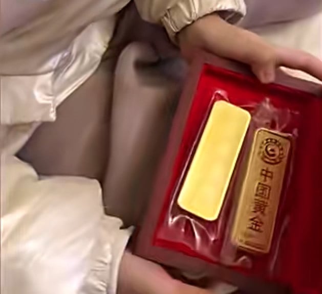 The little girl holds the gold bars. When her parents asked her what they were, she said had no idea. Photo: Baidu