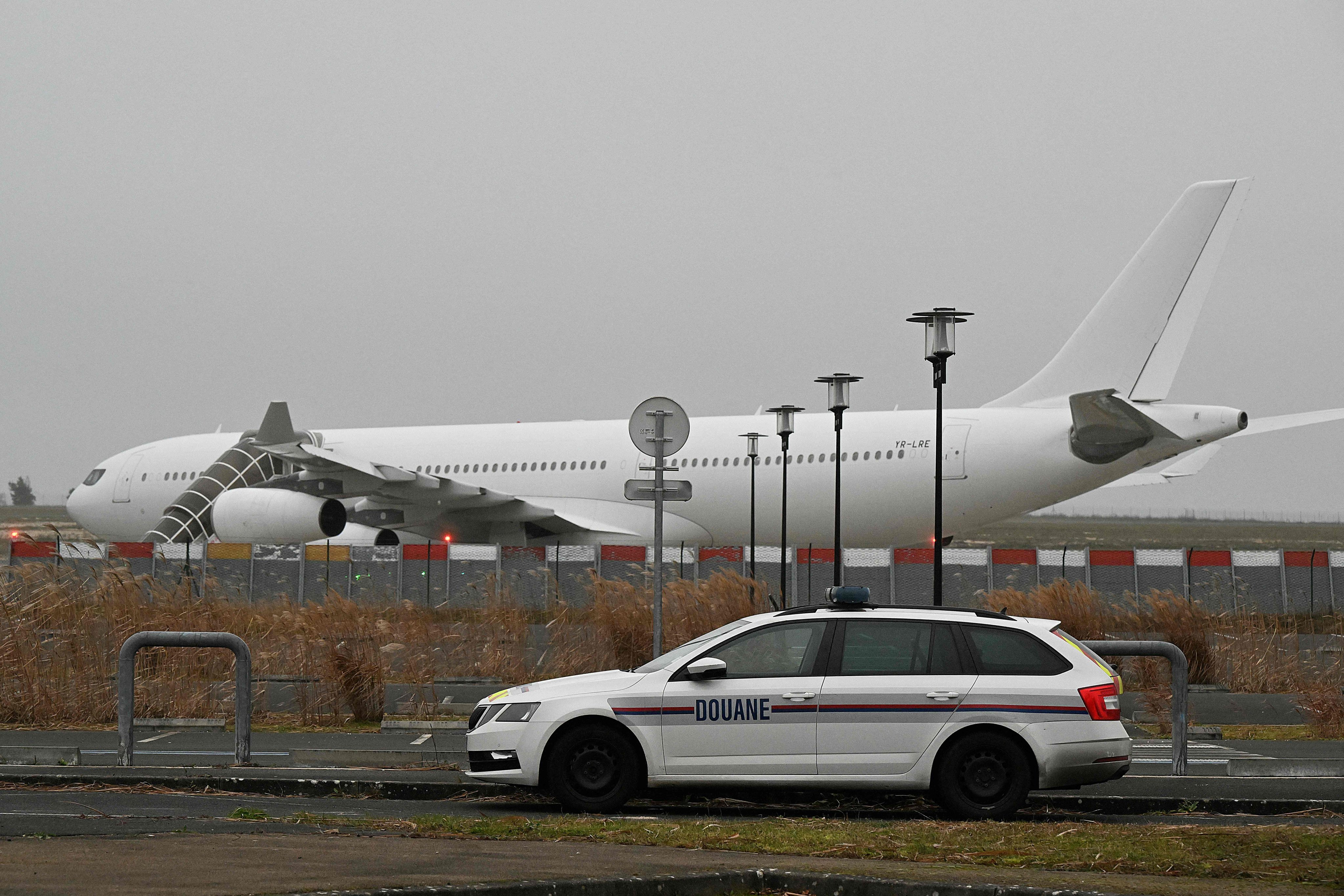 A French customs car with the grounded Airbus A340 in the background at Vatry airport in France. The plane was kept on the tarmac for four days over suspected human trafficking. Photo:  AFP