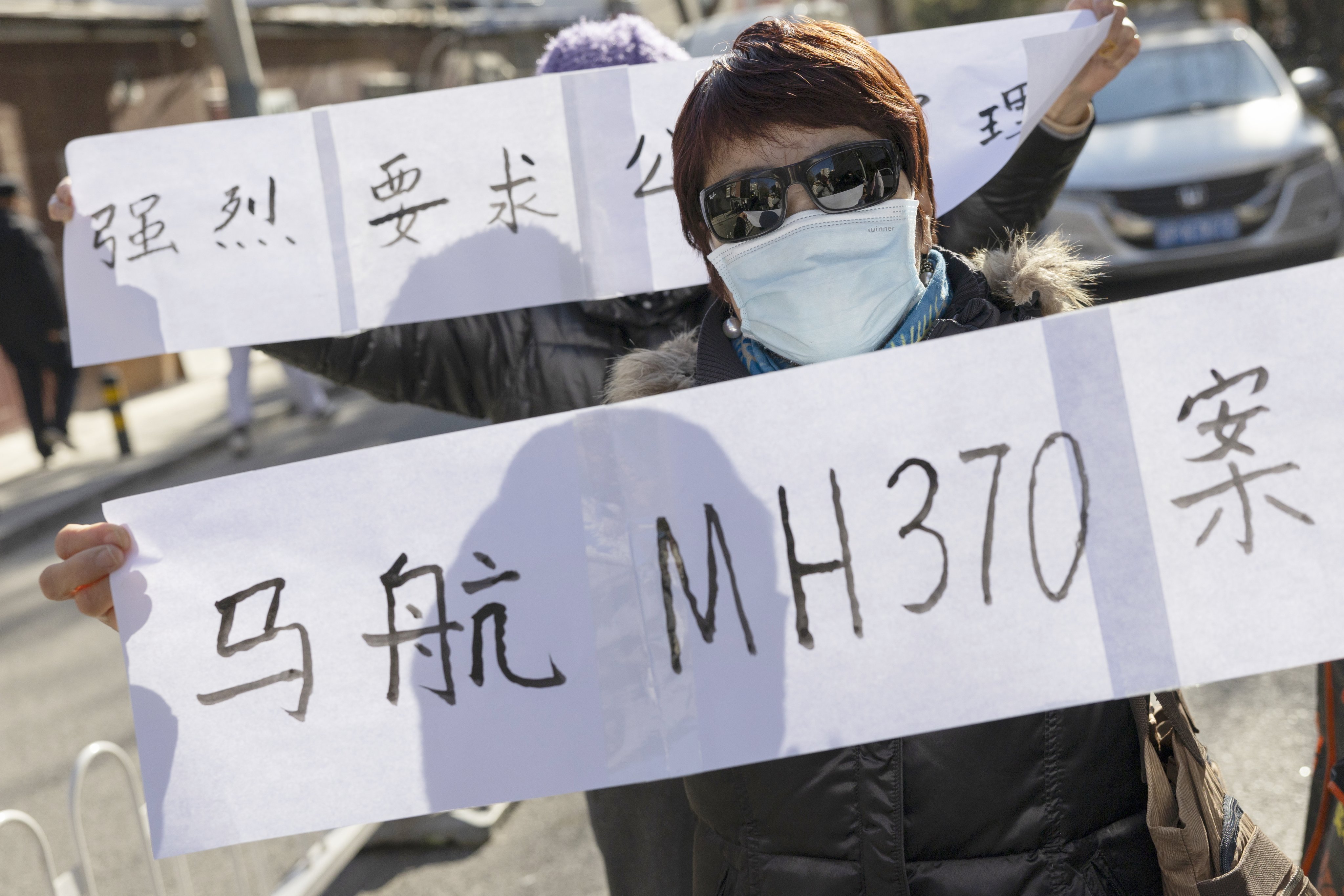 A relative of a missing flight MH370 passenger holds a banner stating “Malaysia Airlines MH370 case” in Chinese after a compensation claim hearing in Beijing on November 27. Photo: EPA-EFE