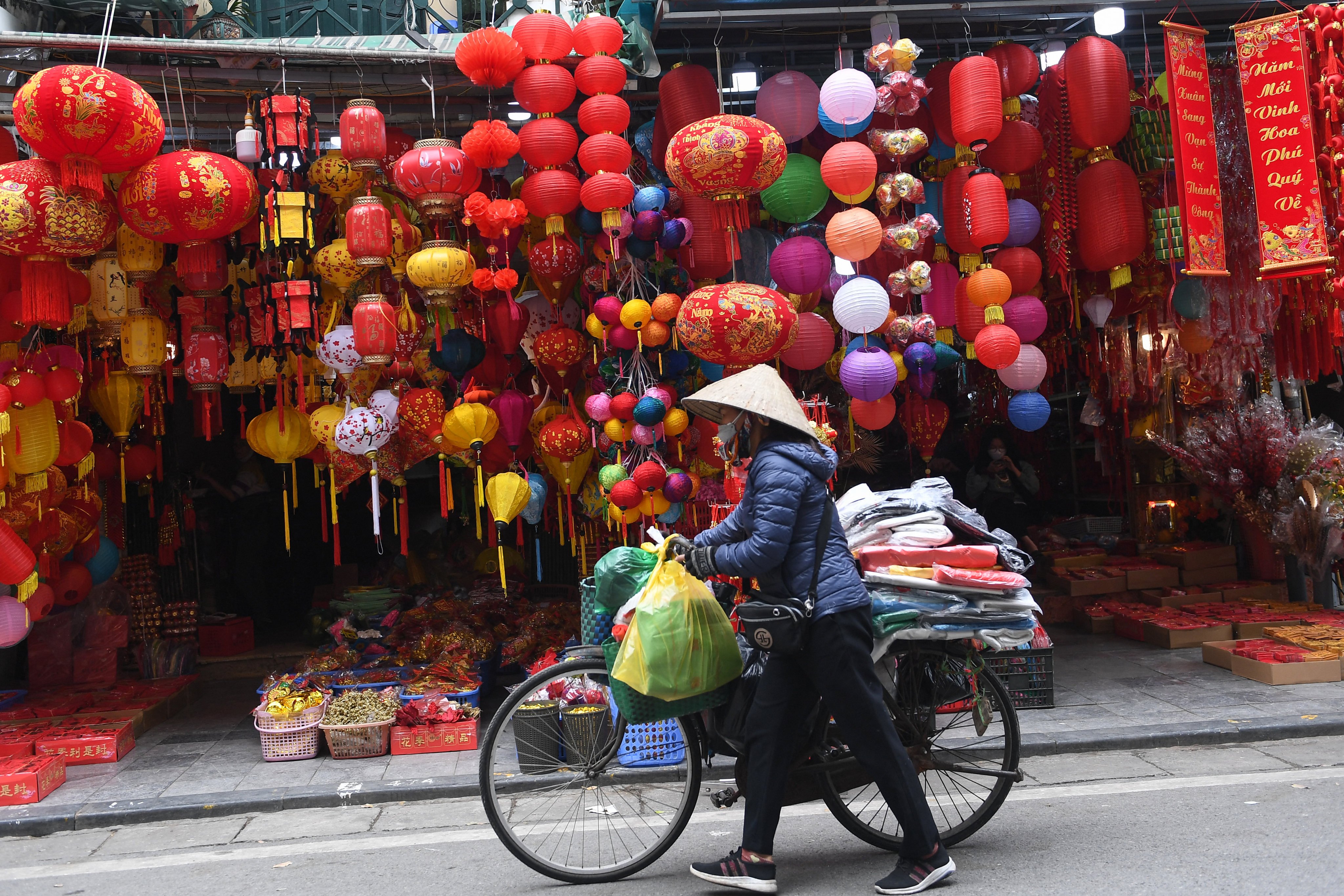 A street vendor pushes her bicycle past a shop selling decorations in the old quarter of Hanoi ahead of the Lunar New Year, or Tet, holiday. The lunar new year is marked with festivities in cultures across Asia, and in their diasporas around the world. Photo: AFP
