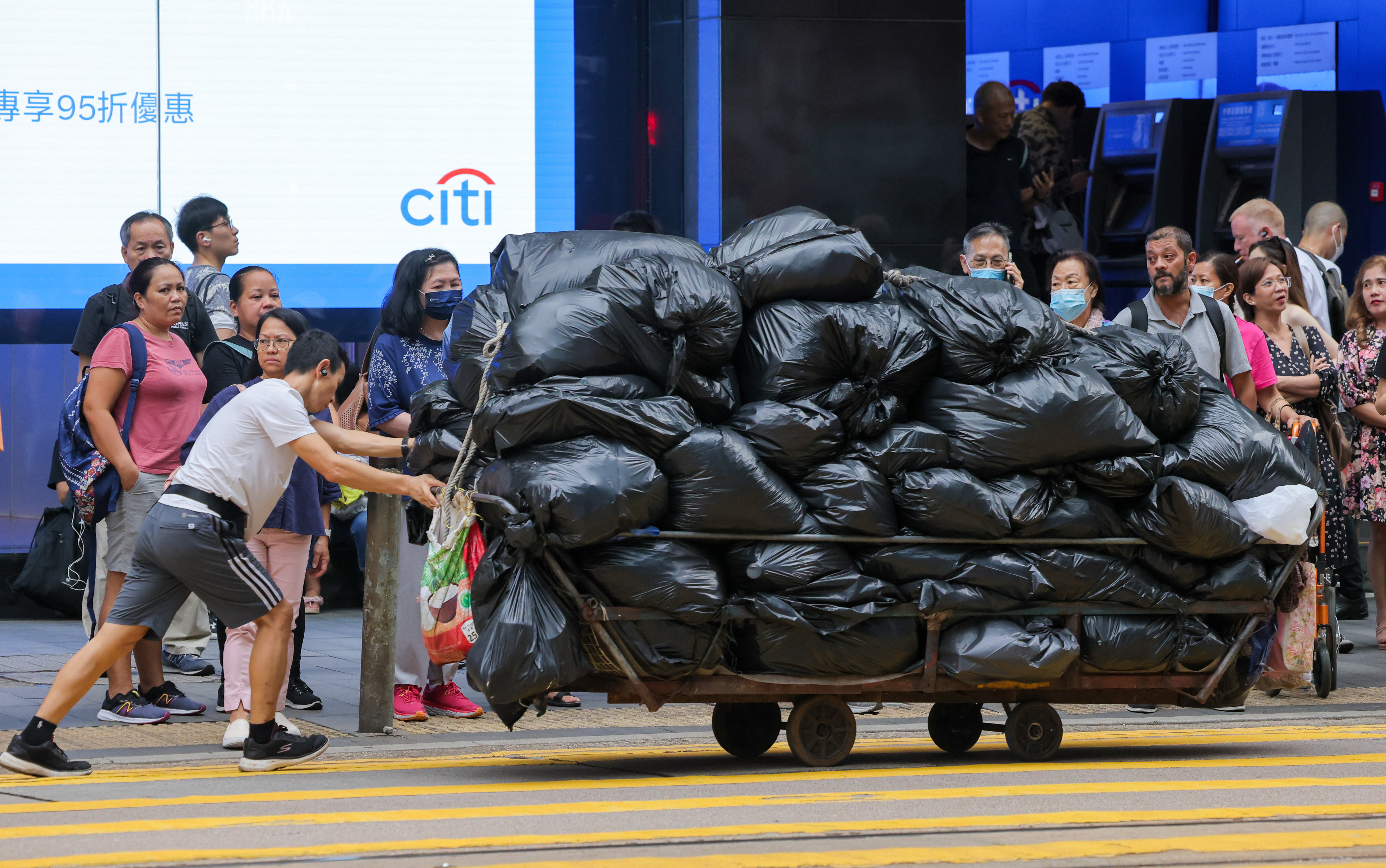 A worker hauls a cart with bags of rubbish in Central. Under a new waste-charging scheme set to  take effect on April 1, residents will be required to buy government-approved plastic bags. Photo: Jelly Tse