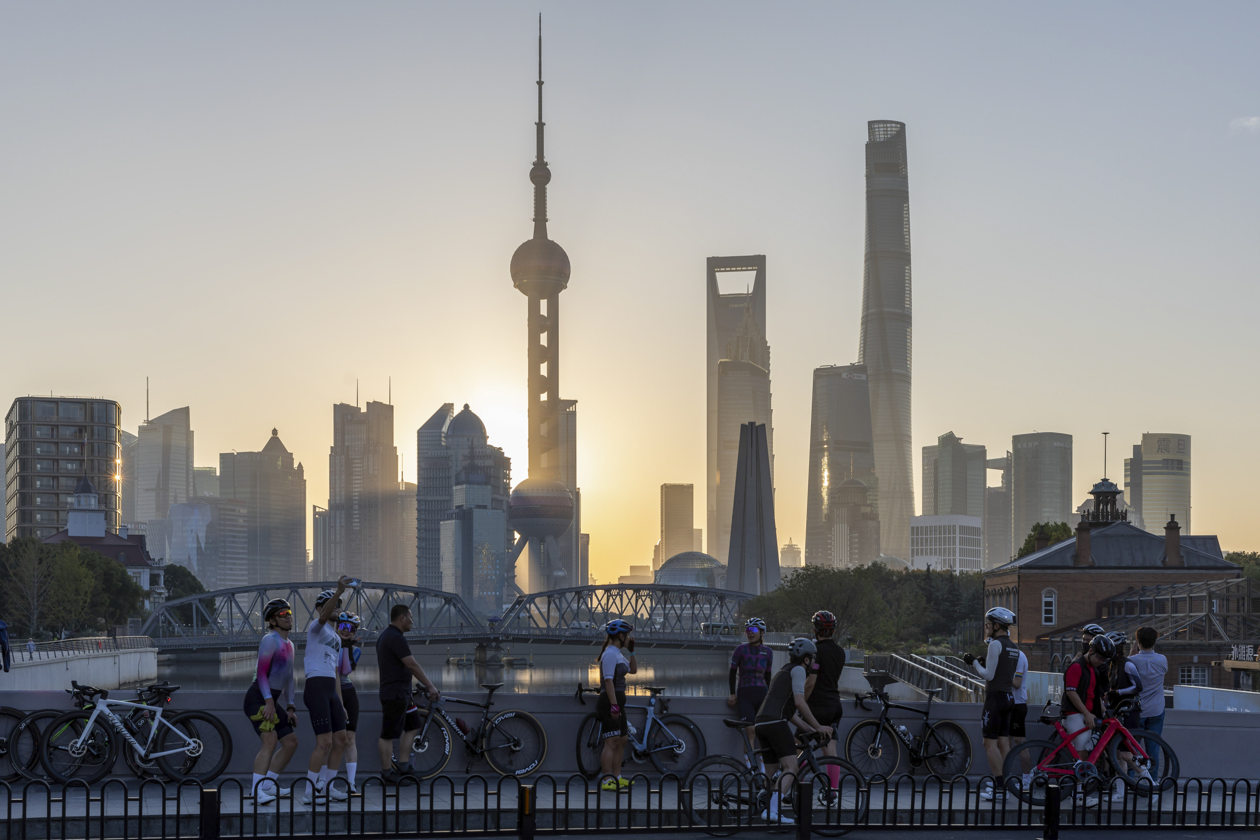 Cyclists take selfies against the backdrop of sunlit skylines in Pudong, China’s financial and commercial hub, in Shanghai, China. Photo: Xinhua via AP