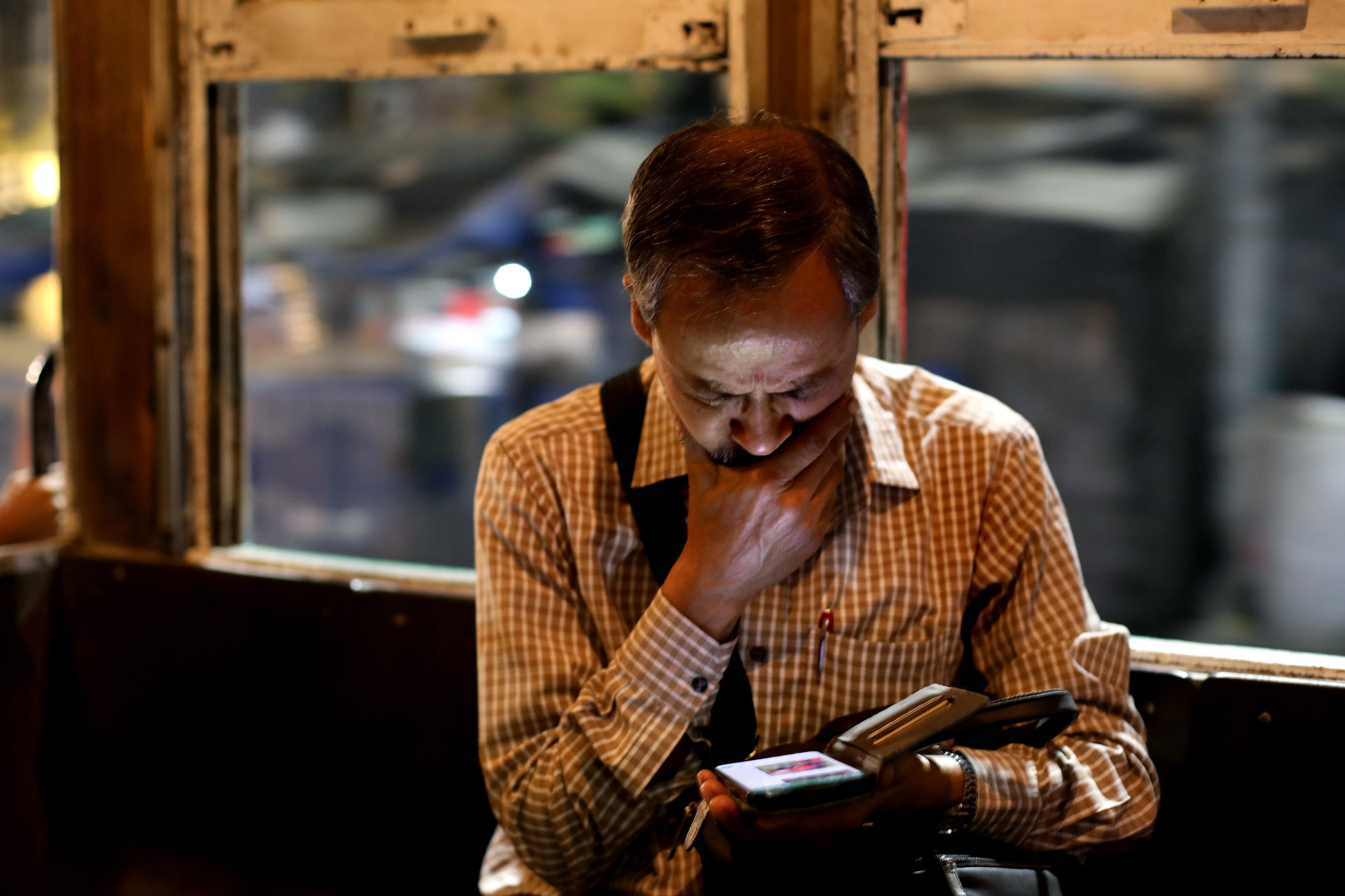 A man checks his mobile phone while commuting in a tram in Kolkata, India. Photo: EPA-EFE