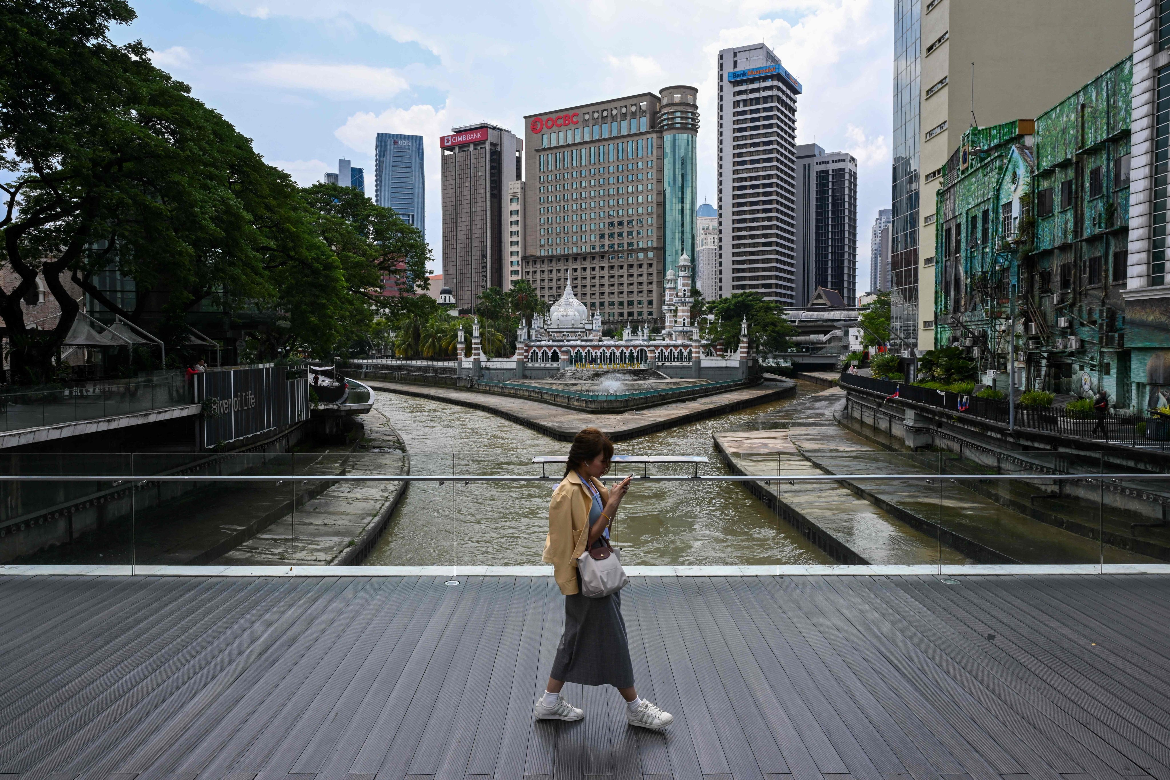 A woman checks her mobile phone as the Masjid Jamek Sultan Abdul Samad is pictured in the background next to commercial buildings in Kuala Lumpur. Concern over data security and protection against breaches is high in Malaysia after repeated revelations of hacks and data theft over recent years. Photo: AFP