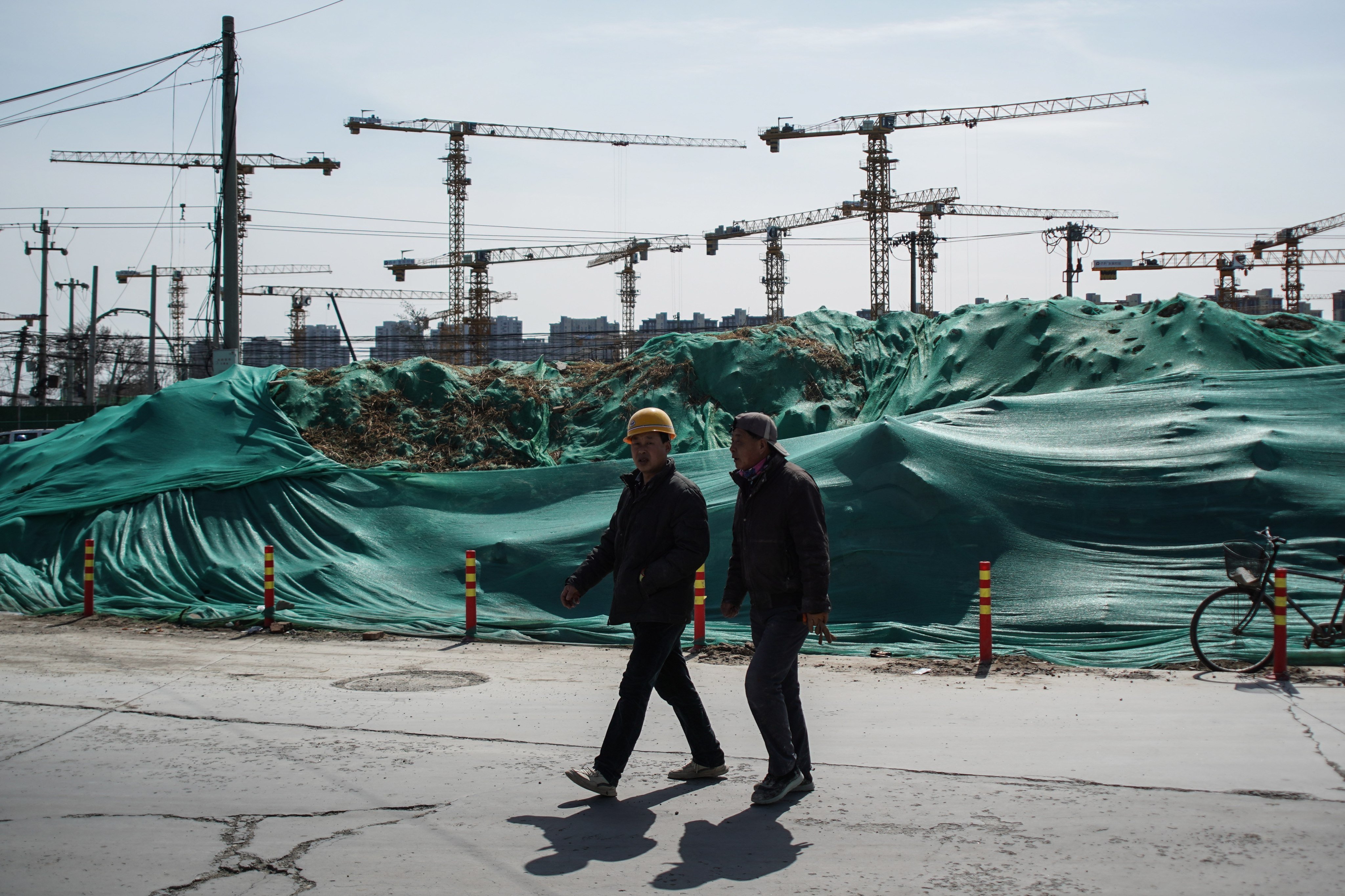 Two migrant workers walk near a construction site in Beijing. Expanding urban registration for migrants could be a source of new consumption for an economy in need of heightened activity. Photo: EPA-EFE