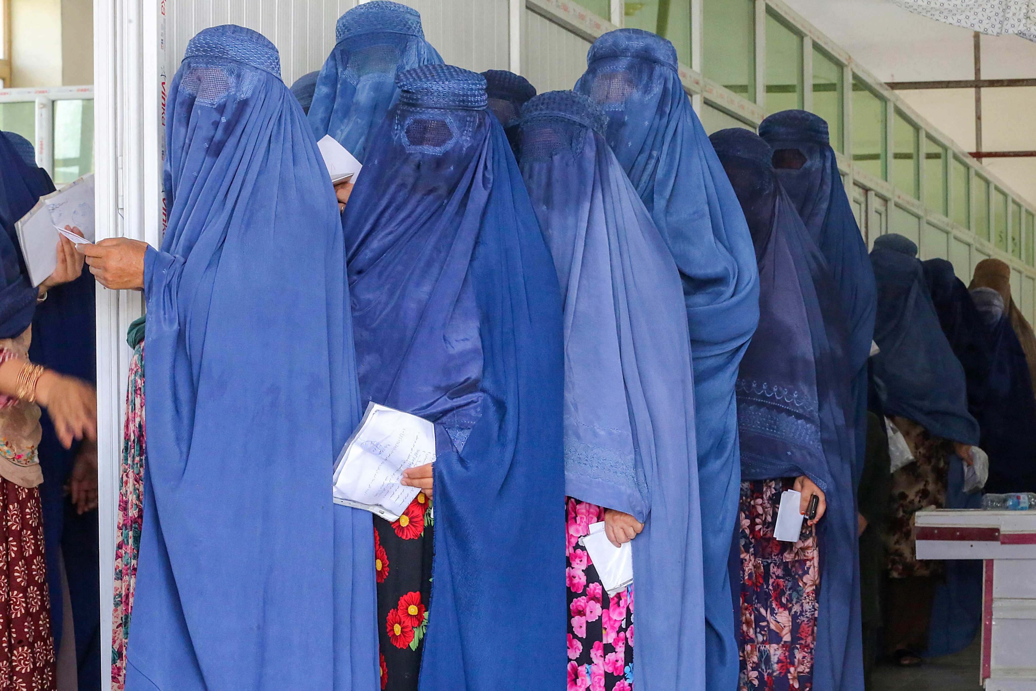 Afghan burka-clad women wait in a queue to receive money as a humanitarian aid from the International Federation of Red Cross and Red Crescent Societies on August 6, 2023. Photo: AFP