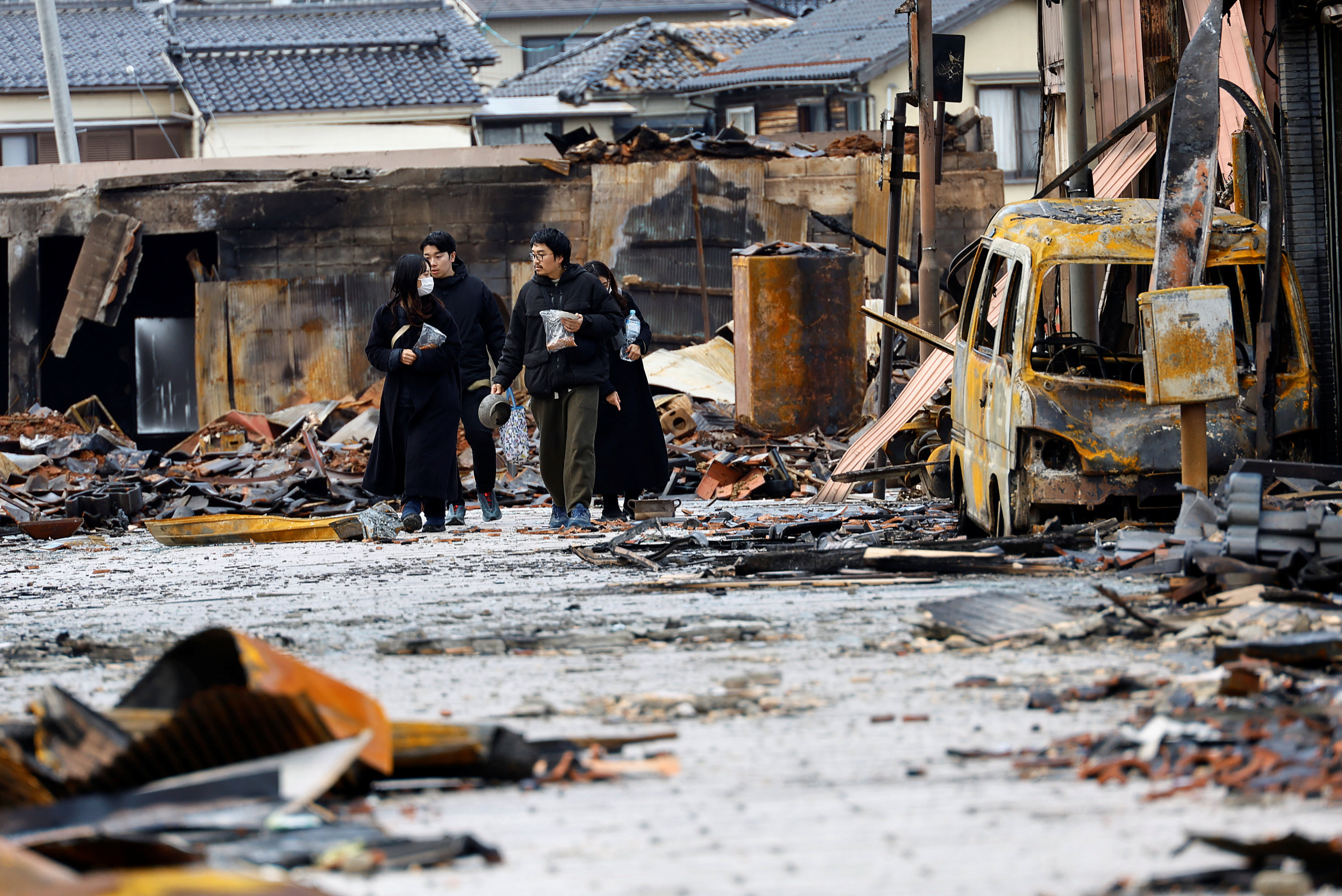 Japanese lacquer artist Kohei Kirimoto searches for his missing cats with family members, near to an “Asaichi” morning market which burnt down in a quake-triggered fire, in Wajima, Japan, on Thursday. Photo: Reuters