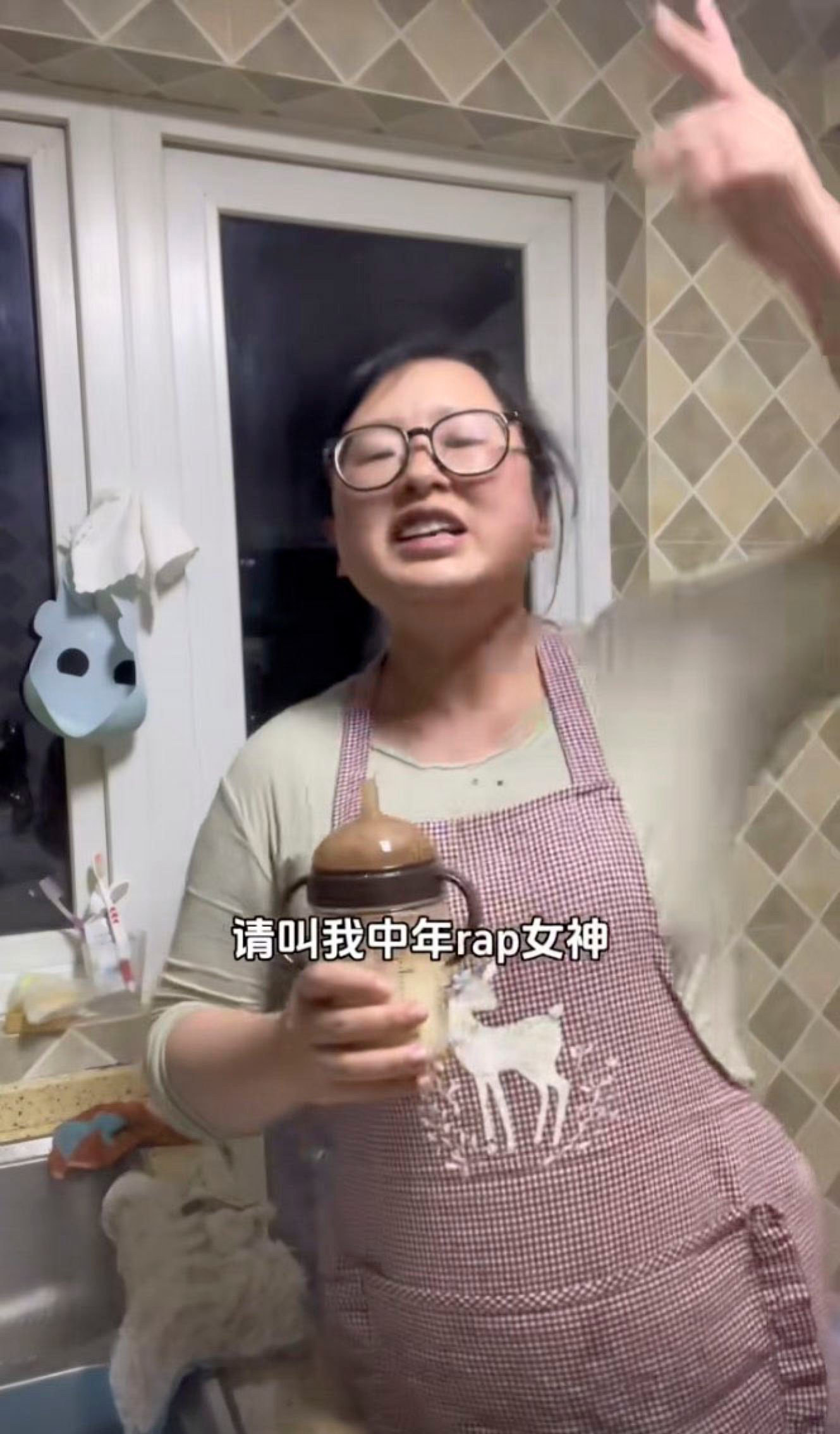 40-year-old mother of two young children, Xie, performs in her kitchen while holding a feeding bottle. Photo: Douyin