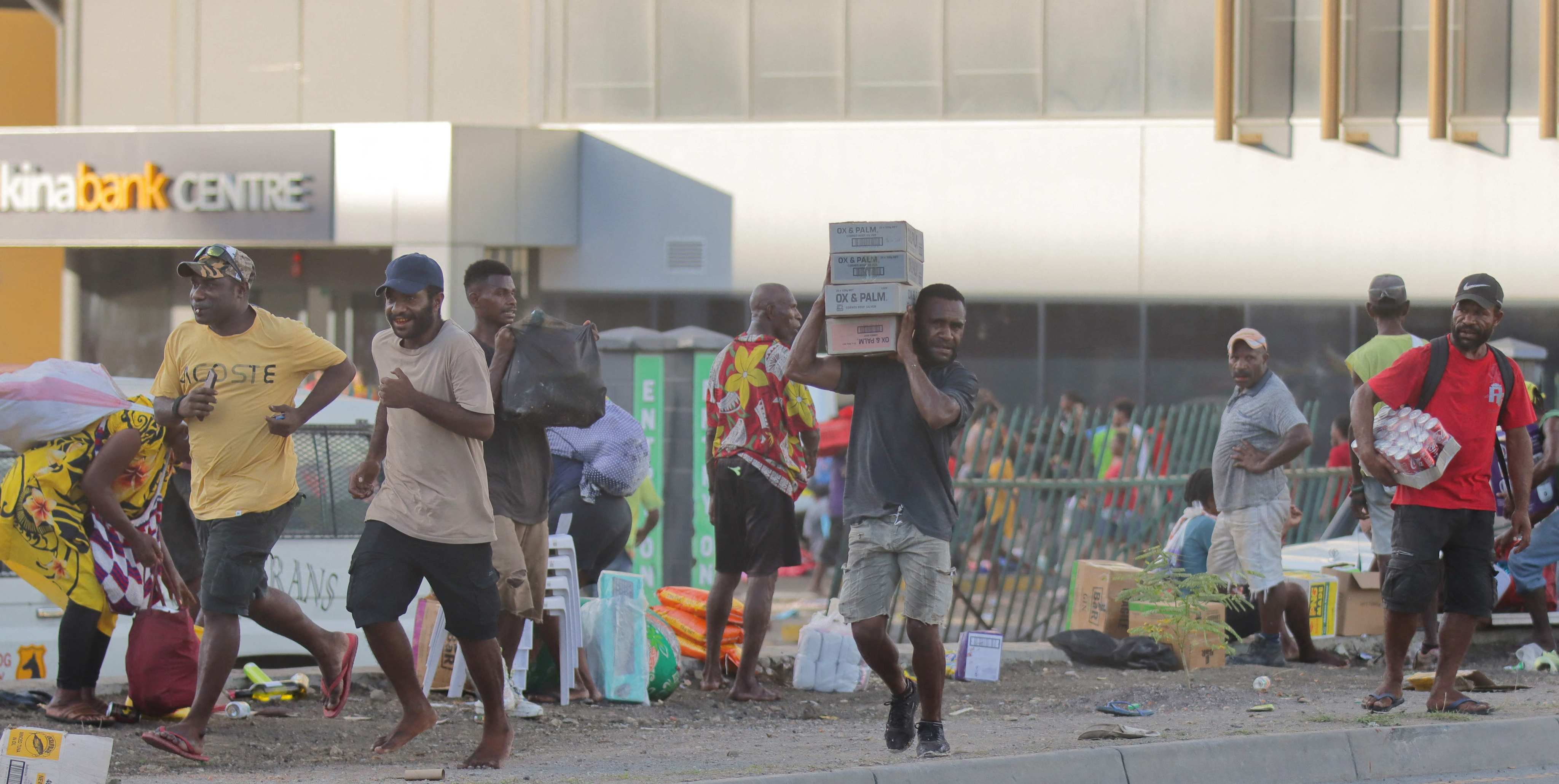 People carry looted goods amid a state of unrest in Port Moresby on January 10. Photo: AFP 