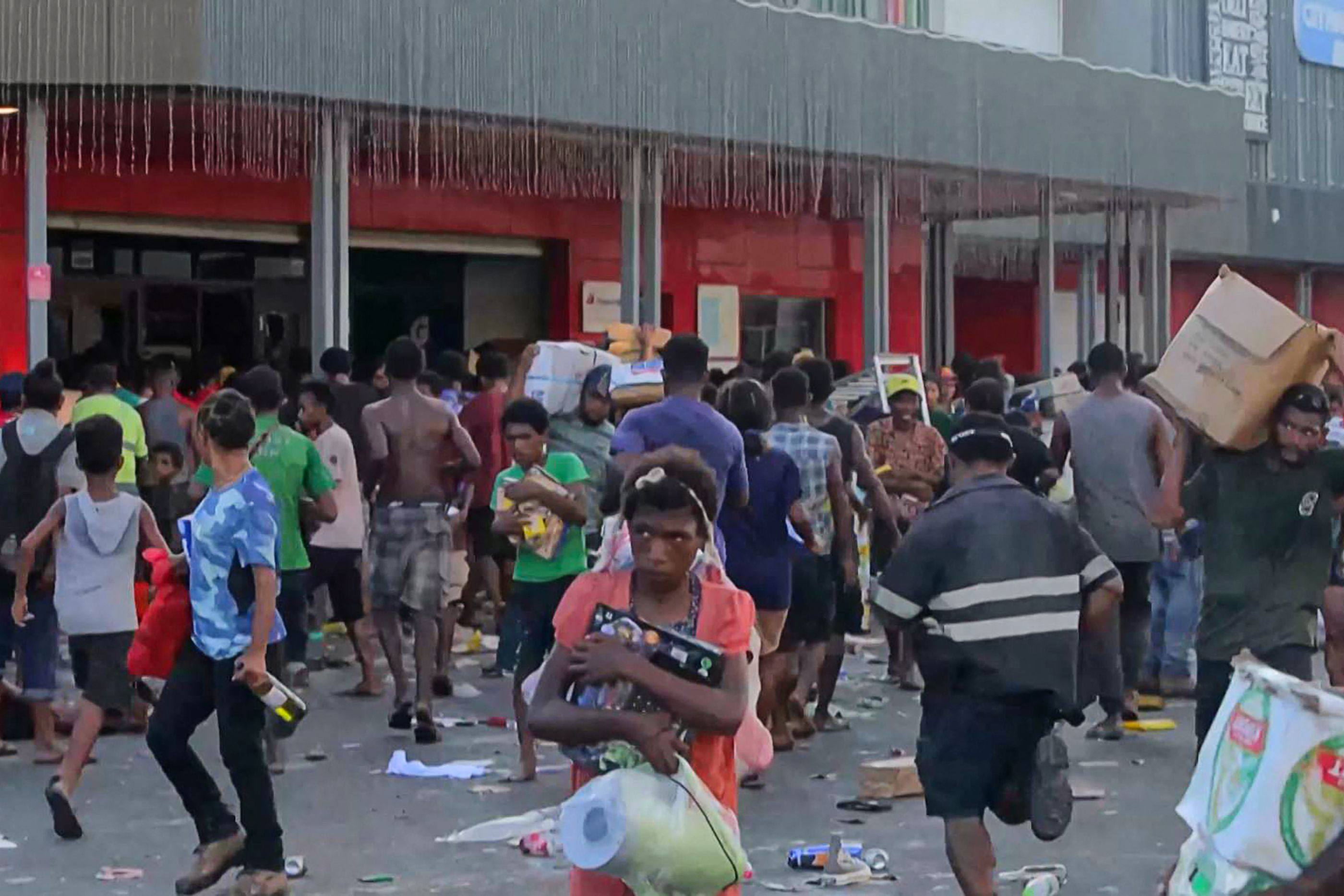 Looters leave shops with goods amid a state of unrest in Port Moresby on  January 10. Photo: AFP 