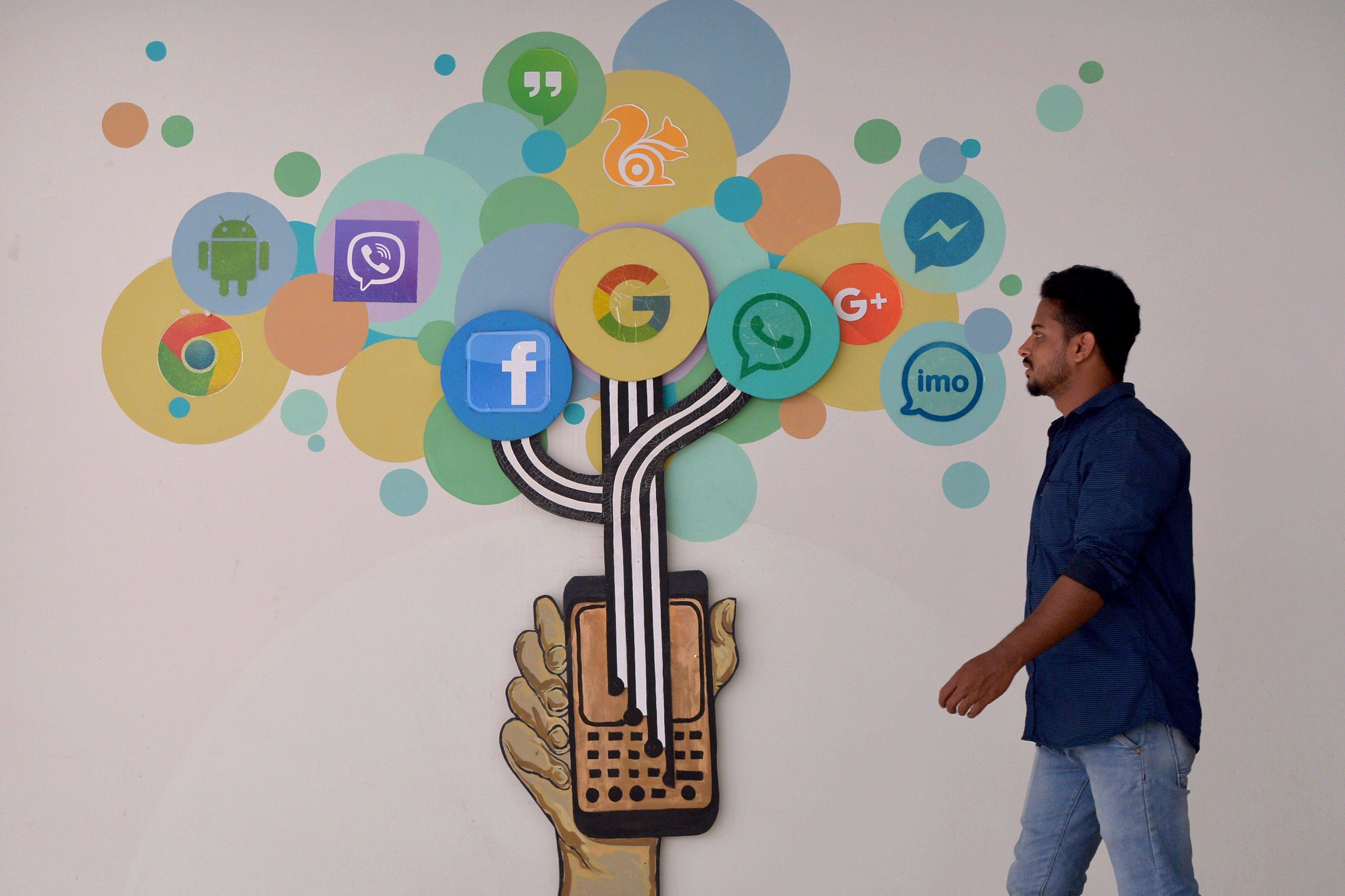 A visitor passes a mural depicting various social media sites logos in Bangalore. Photo: AFP