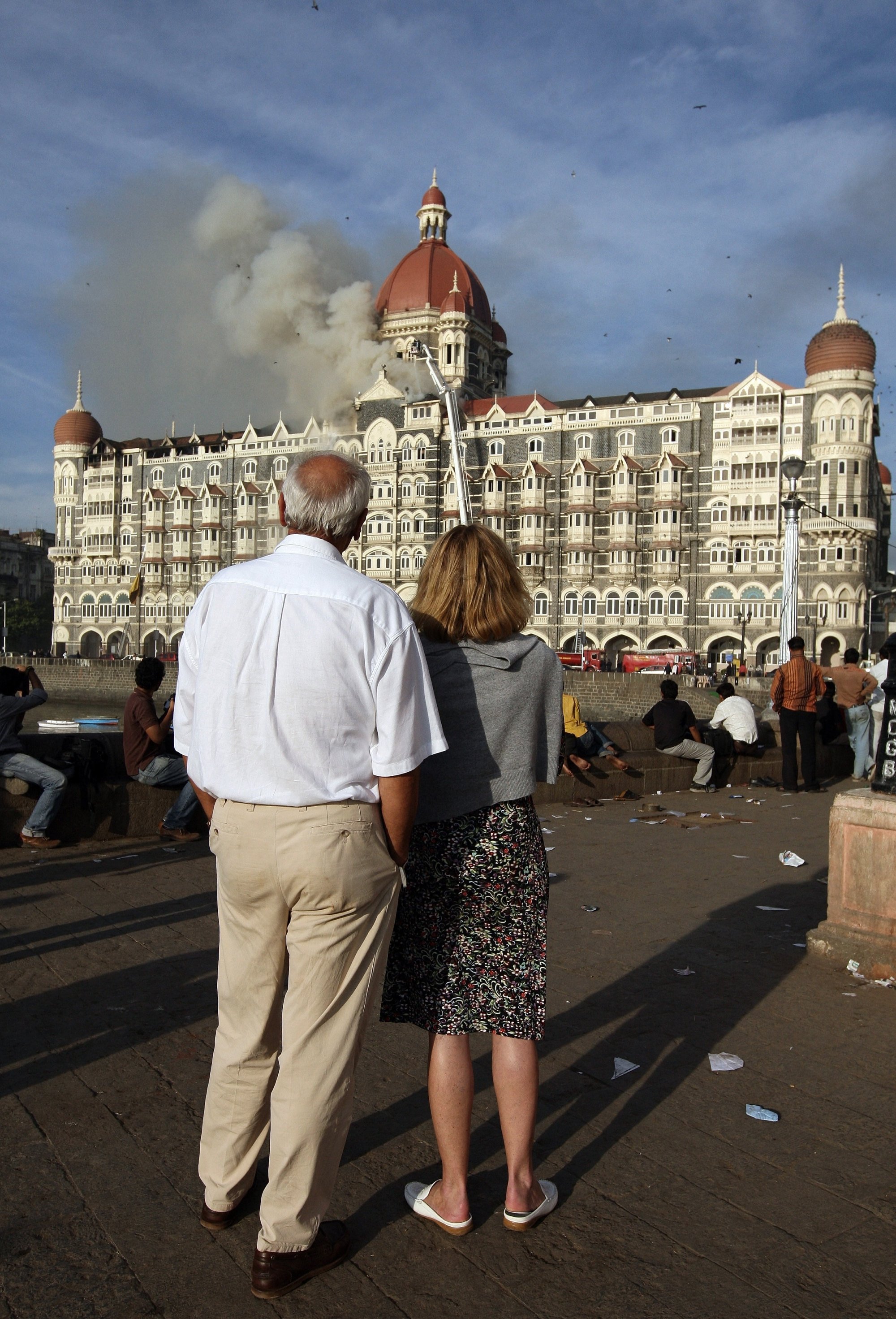 Tourists watch as smoke billows out of the Taj Mahal Palace Hotel on November 27, 2008, after terrorists attacked it. Photo: AFP
