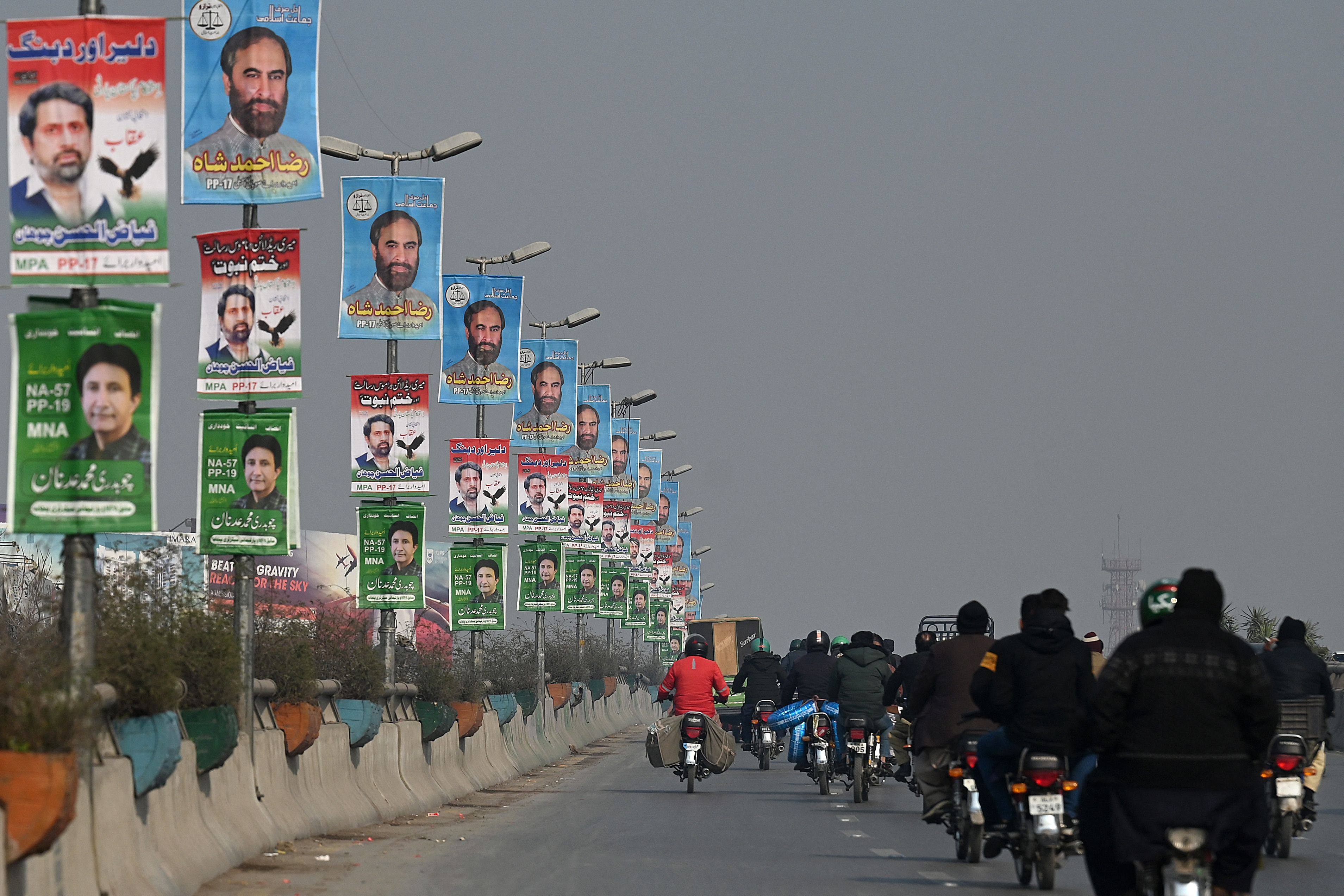 Commuters move past election campaign posters in Rawalpindi, Pakistan, on Tuesday, ahead of the coming general election. Photo: AFP