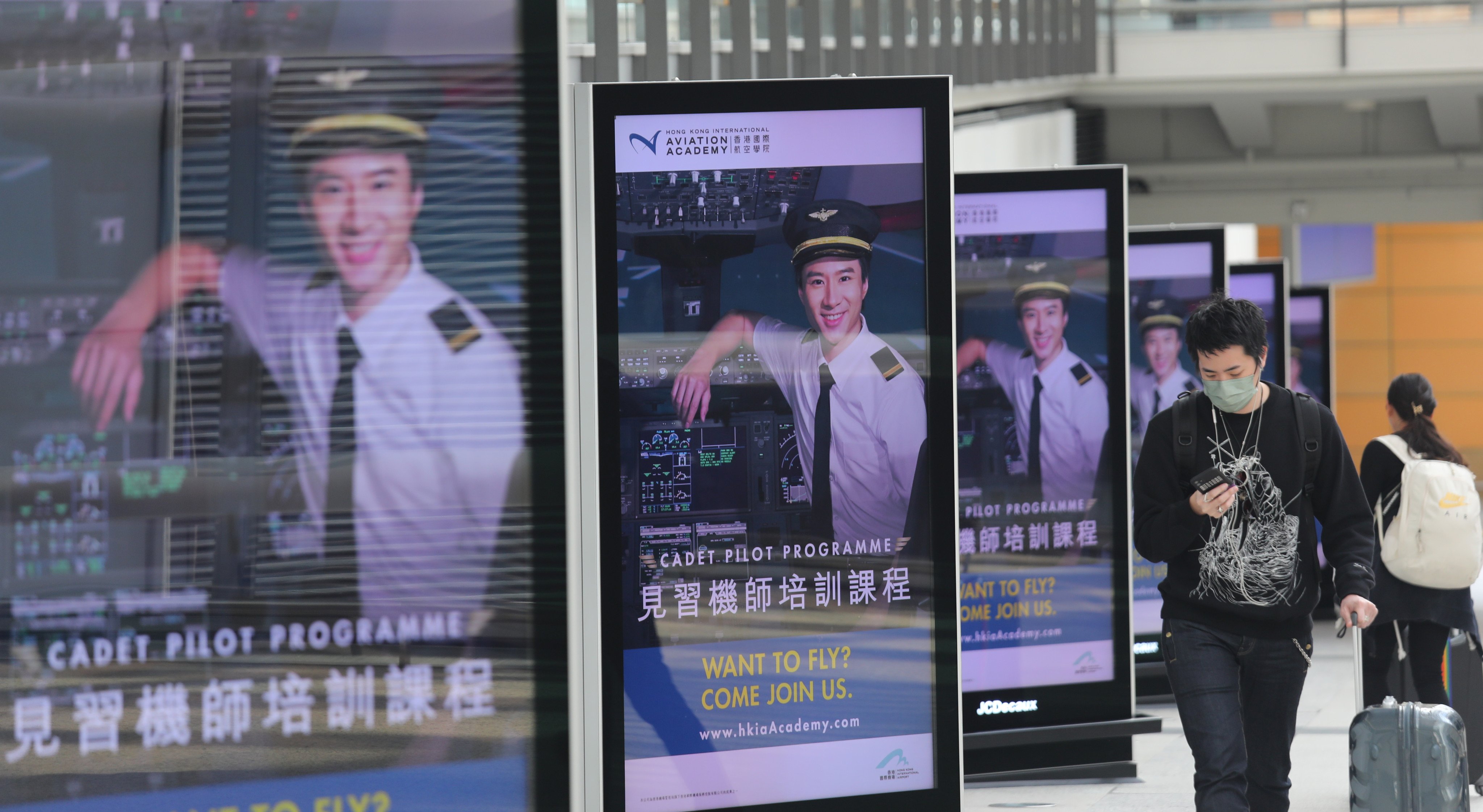 People walk past a line of Cathay recruitment advertisements at Hong Kong International Airport. The carrier pledged no new rounds of service changes beyond the Lunar New Year holiday. Photo: Xiaomei Chen