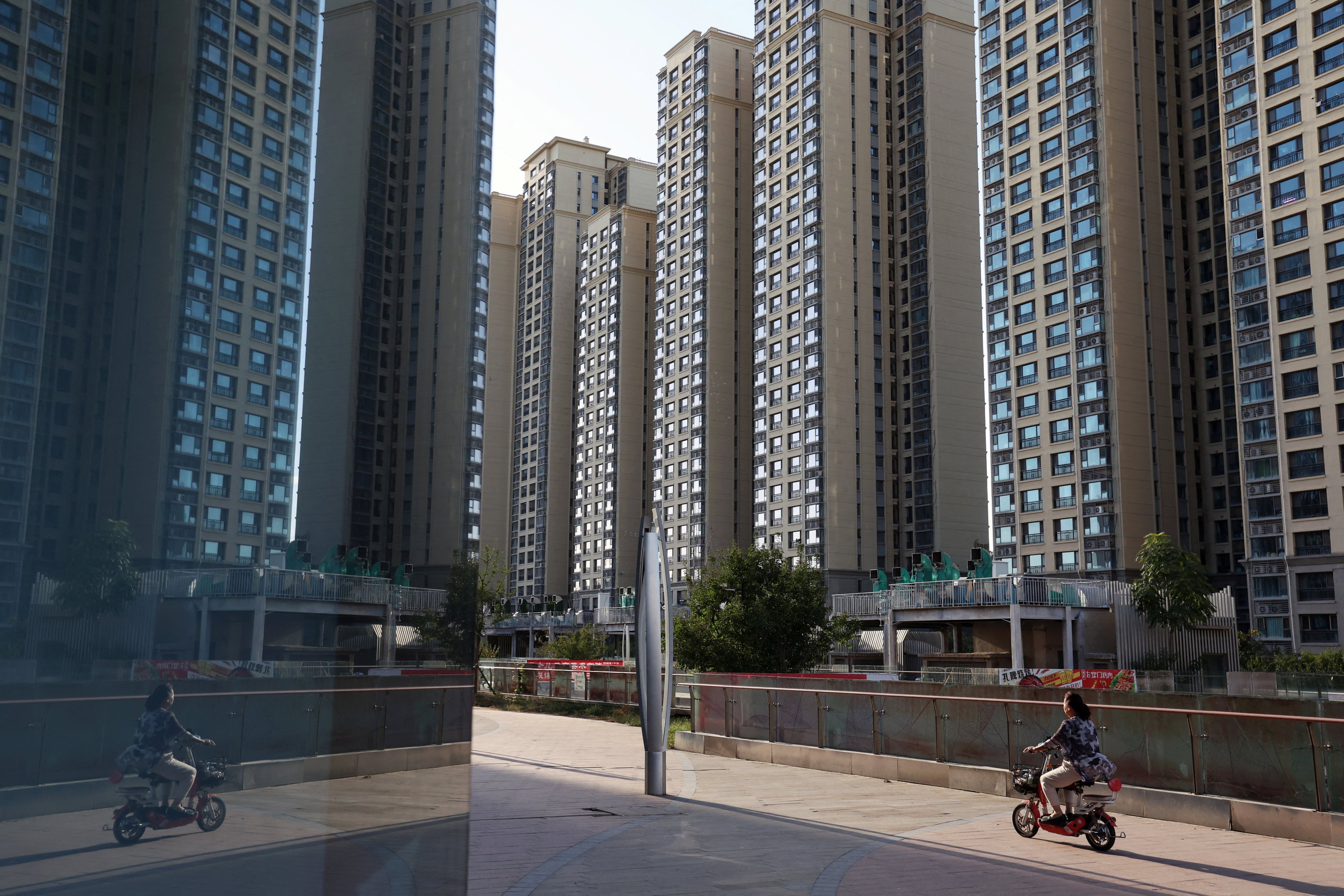 A woman rides a scooter past residential buildings at an Evergrande residential complex in Beijing on September 27, 2023. Photo: Reuters