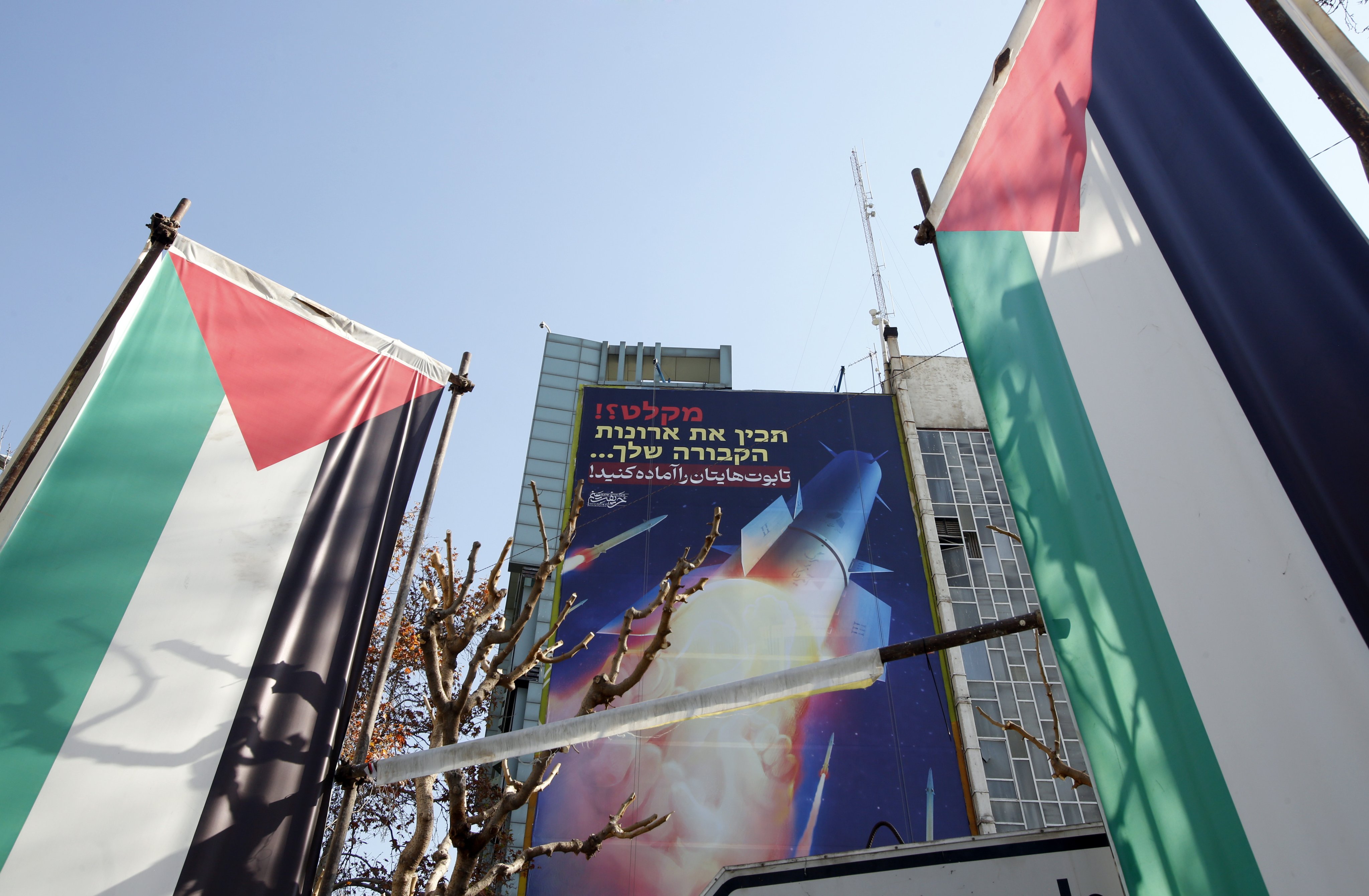 Palestinian flags and a billboard depicting Iranian missiles are seen in Tehran, Iran on Tuesday with a message in Persian and Hebrew reading: “Prepare your coffins”. Photo: EPA-EFE