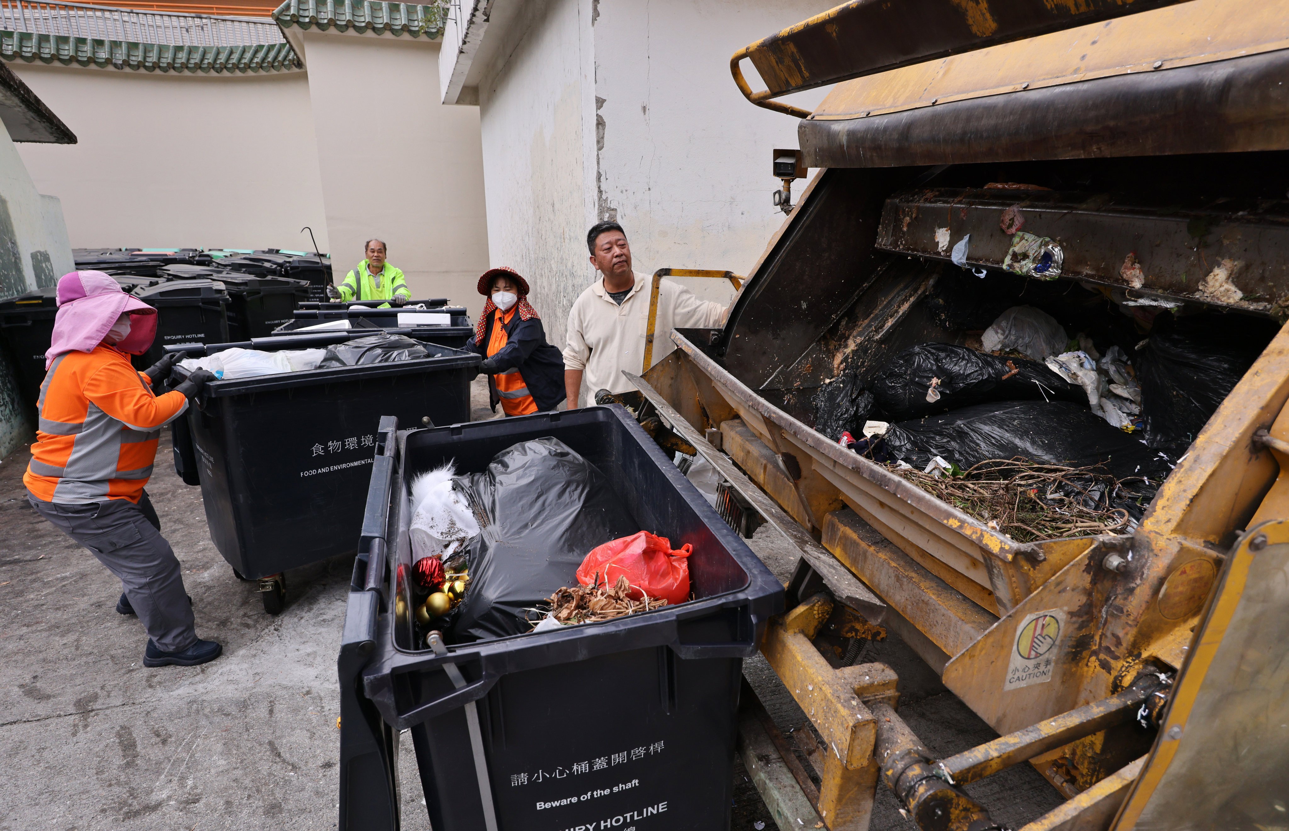 Workers handle rubbish in Tai Wai. City leader John Lee has told the environment minister to spread the word about the waste-charging scheme. Photo: May Tse