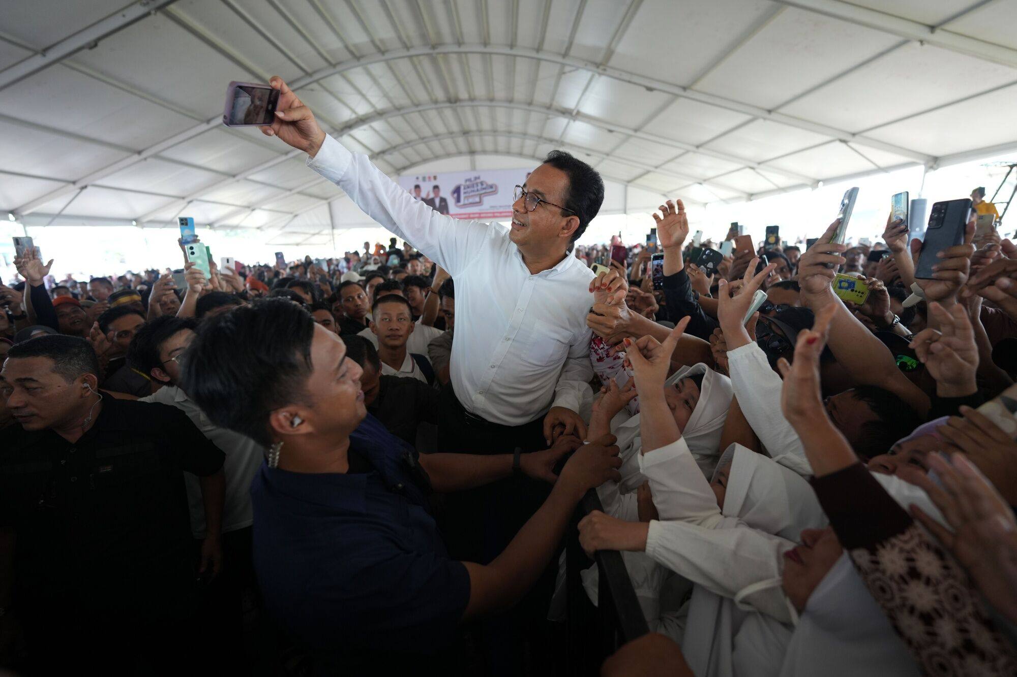 Anies Baswedan takes a selfie with his supporters during a campaign rally in Bone regency, South Sulawesi, Indonesia. Photo: Bloomberg