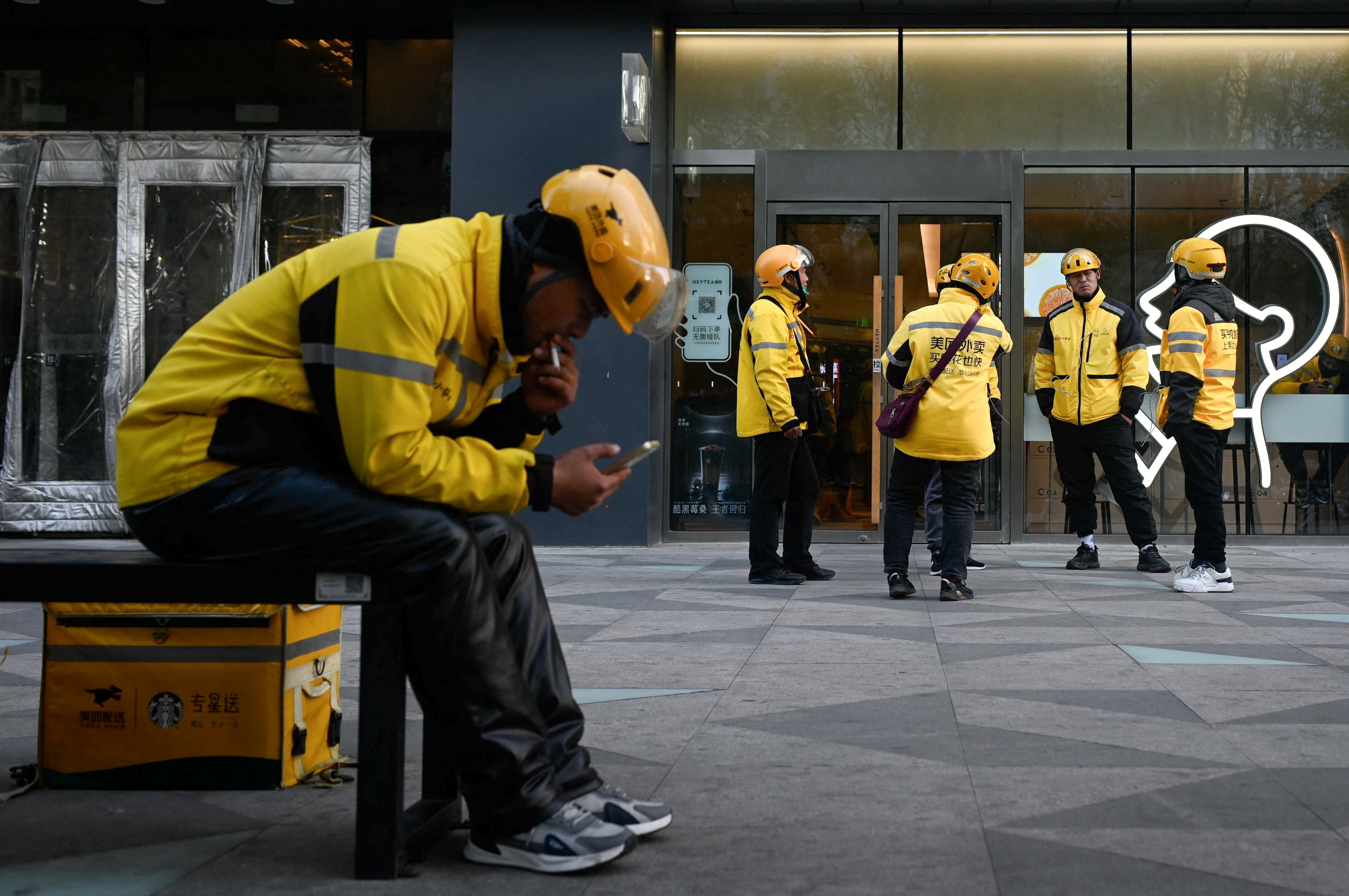 A group of Meituan couriers waits for order in Beijing on November 16, 2023. Photo: AFP