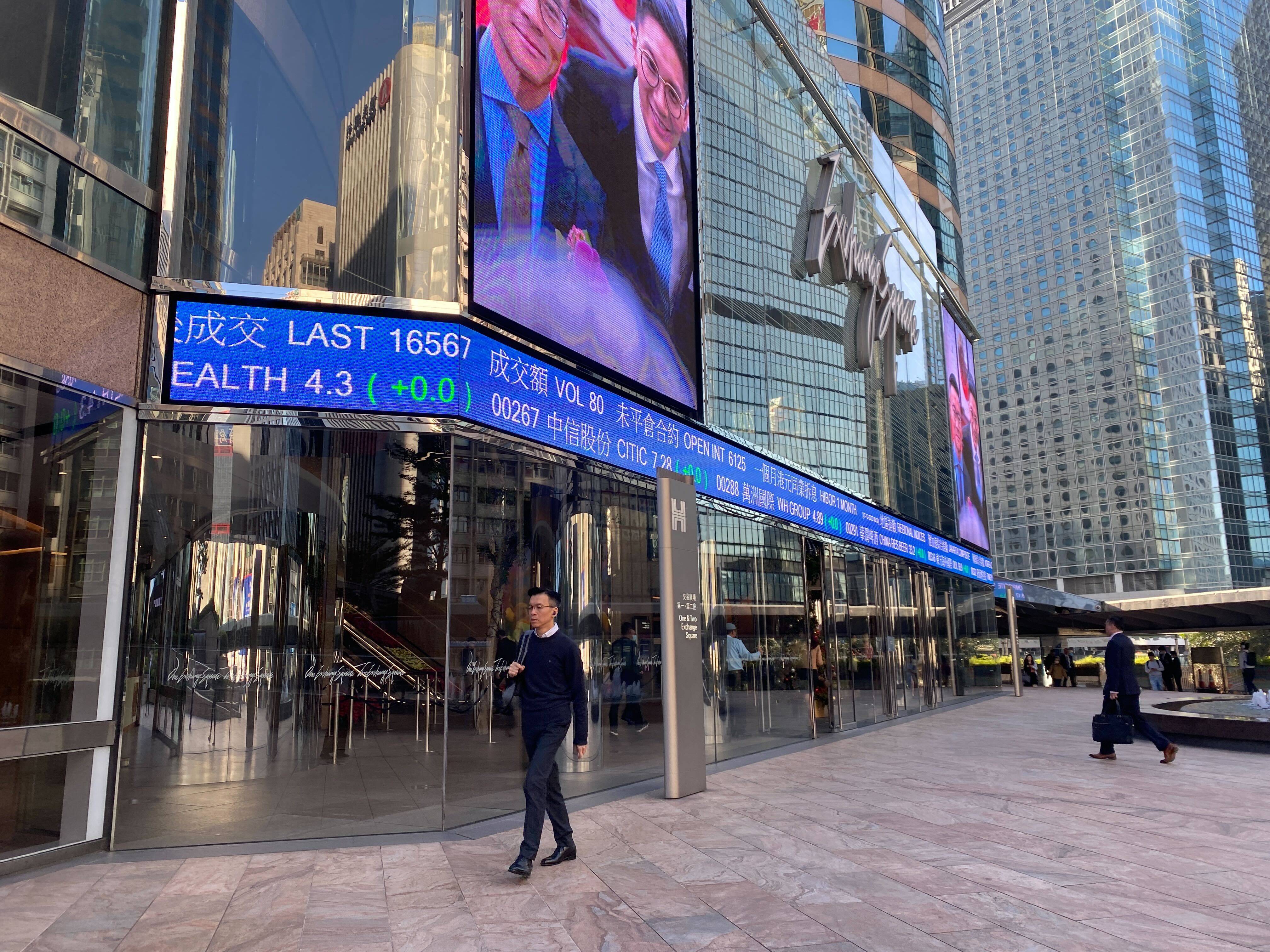 People walking outside the Exchange Square in Central, Hong Kong with tickers showing stock prices on December 7, 2023. Photo: Li Jiaxing