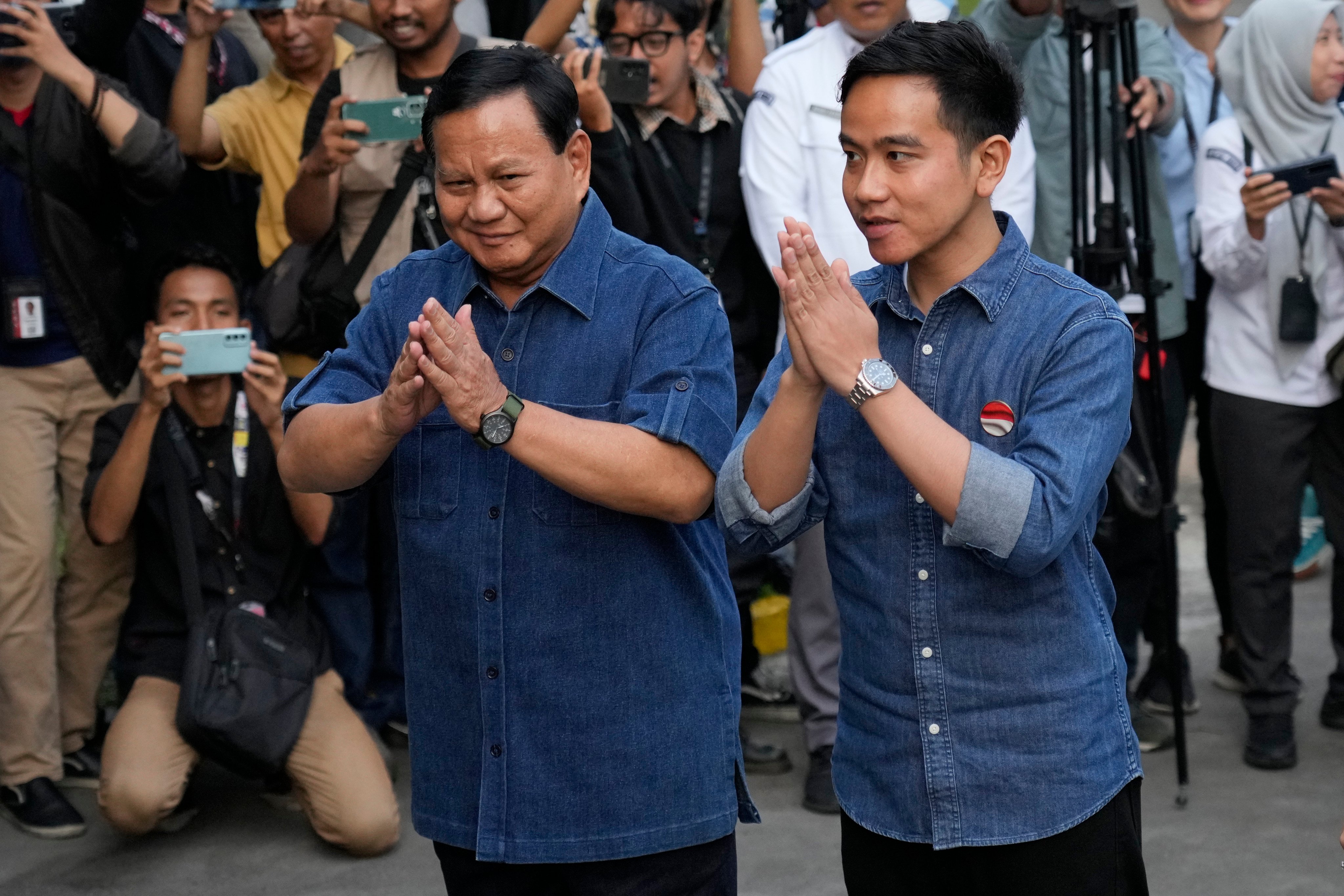 Indonesian presidential candidate Prabowo Subianto (left) and his running mate Gibran Rakabuming Raka, the eldest son of President Joko Widodo, greet reporters on arrival for the medical check-up required to stand in the presidential election, at Gatot Subroto Army Hospital in Jakarta, Indonesia, on October 26. The world’s third-largest democracy will hold its legislative and presidential elections on February 14. Photo: AP 