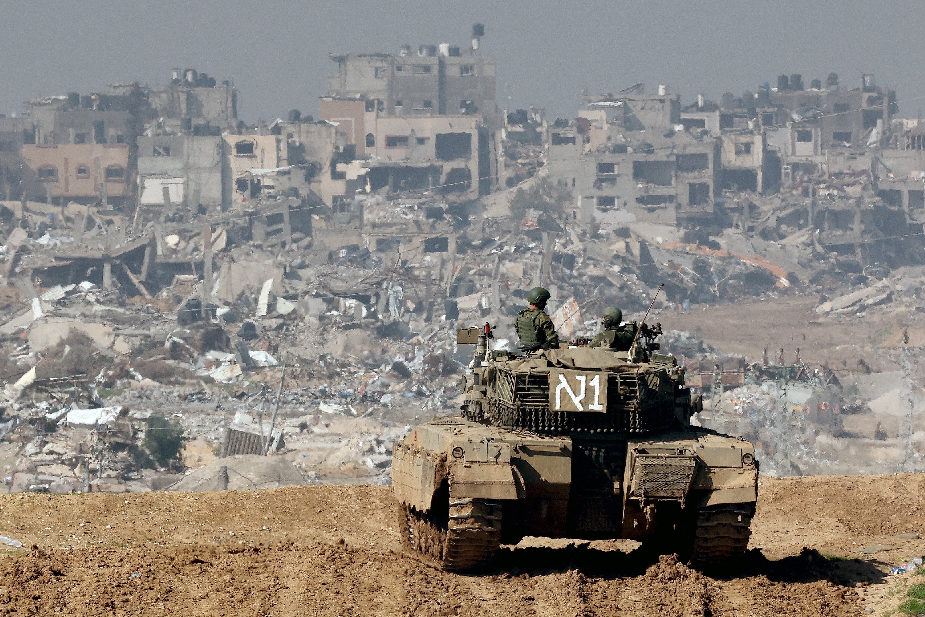 An Israeli tank and damaged buildings in the Gaza Strip in the background. Photo: AFP