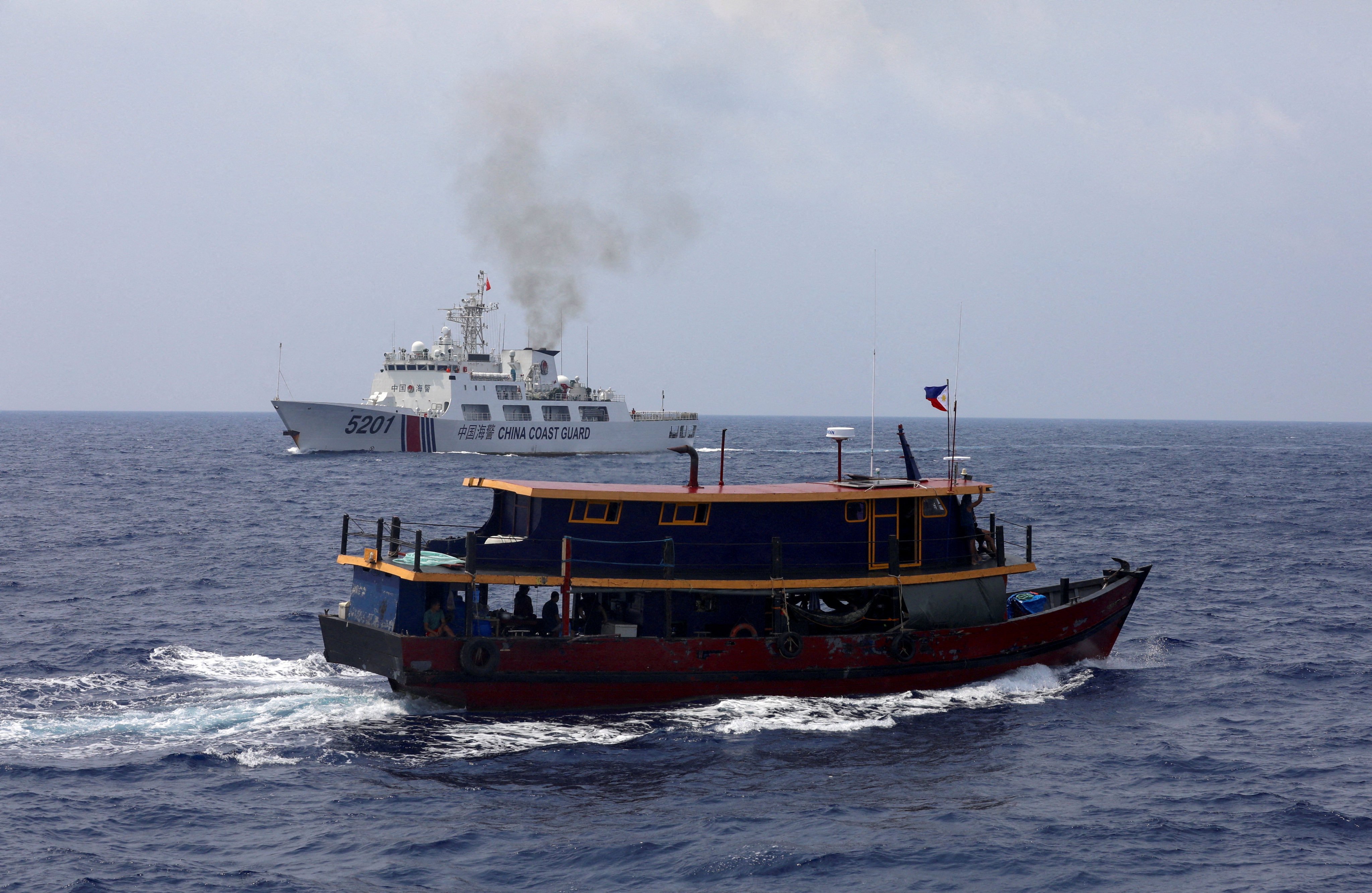 A Philippine supply boat sails near a Chinese Coast Guard ship during a resupply mission for Filipino troops stationed at a grounded warship in the South China Sea, on October 4, 2023. Photo: Reuters