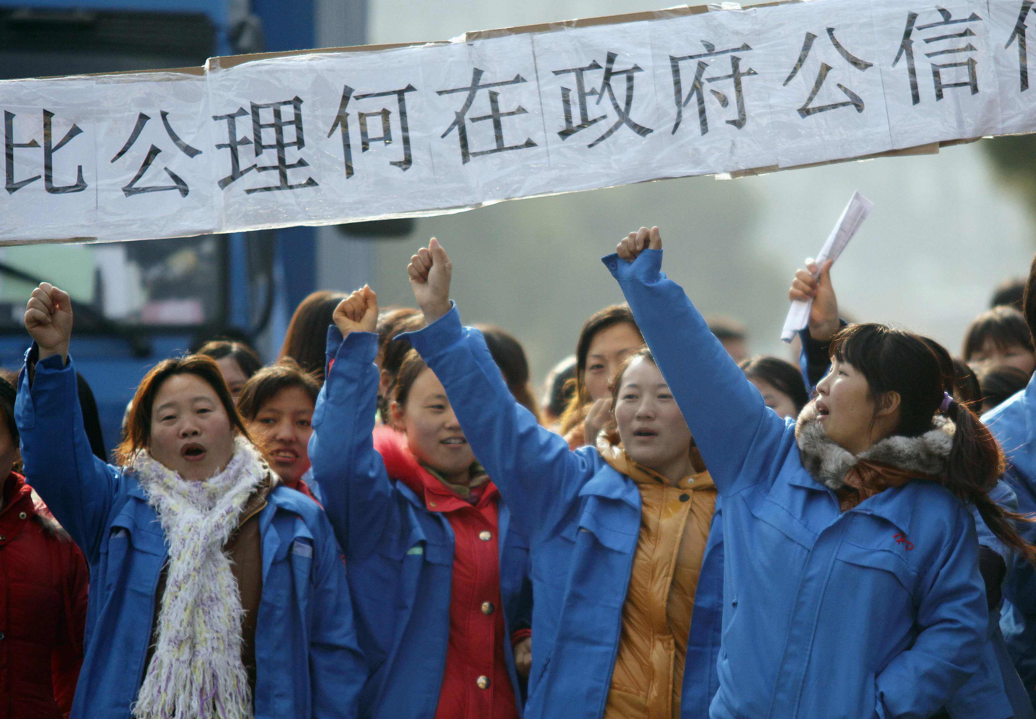 Striking workers hold a banner asking, among other things, how they can trust the government, as they protest against planned lay-offs at a factory in Shanghai on December 2, 2011. Photo: Reuters