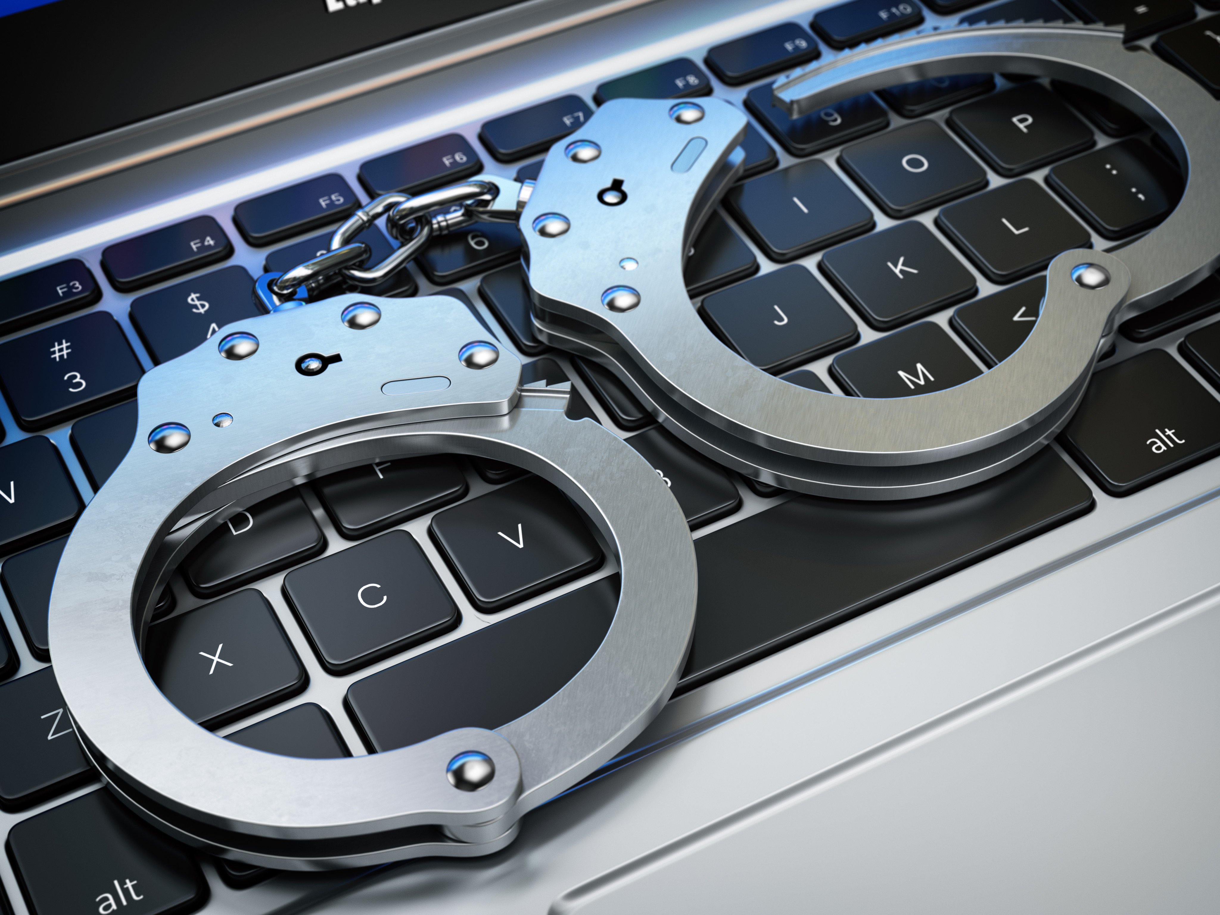 Handcuffs on a laptop keyboard. Photo: Shutterstock