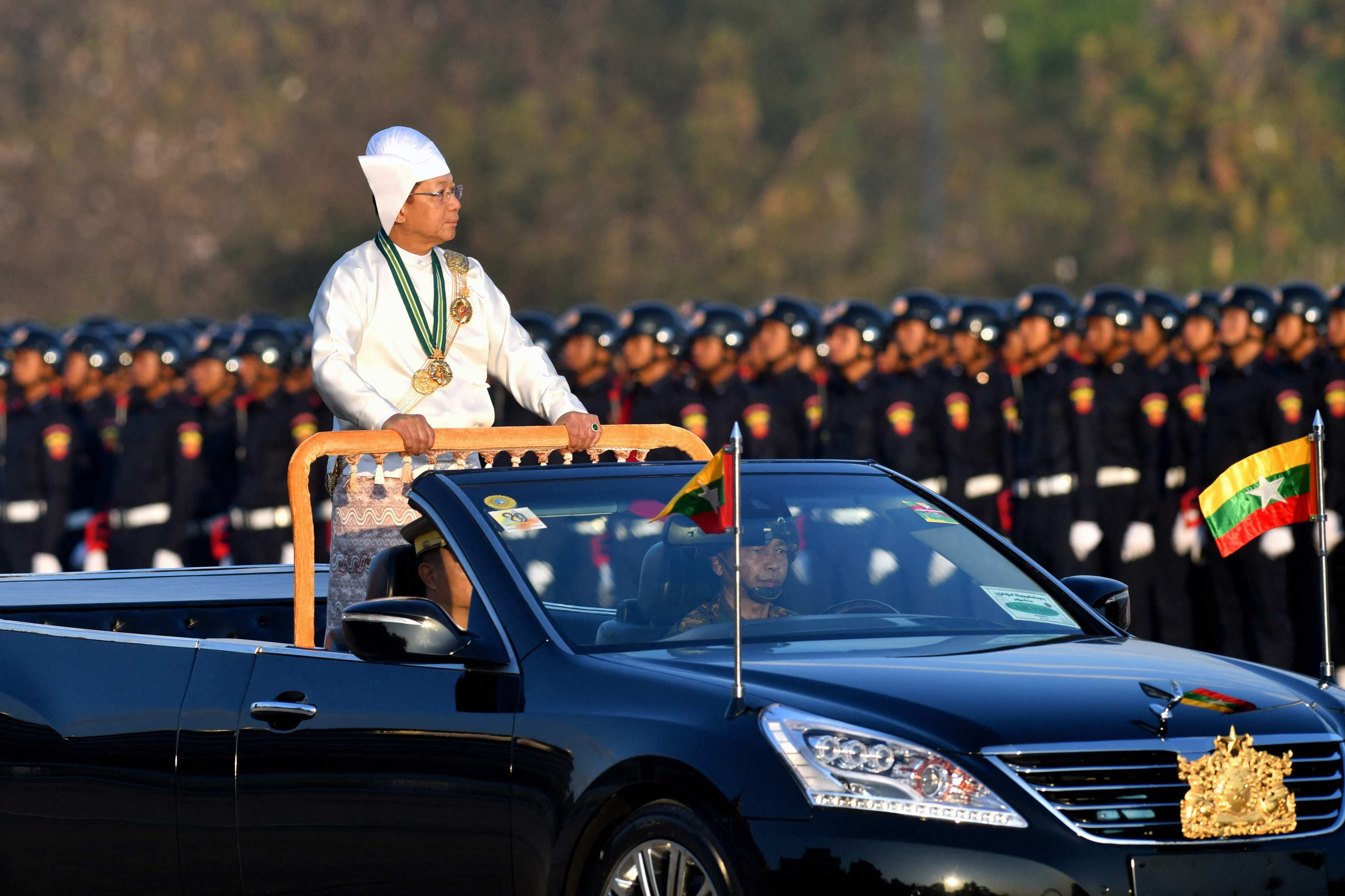 (FILES) Myanmar’s military chief Min Aung Hlaing stands in a car as he oversees a military display at a parade ground to mark the country’s Independence Day in Naypyidaw on January 4, 2023. Myanmar’s National Defence and Security Council agreed July 31, 2023 to extend the country’s state of emergency by six months, state media said, likely delaying elections the junta had pledged to hold by August. (Photo by AFP)