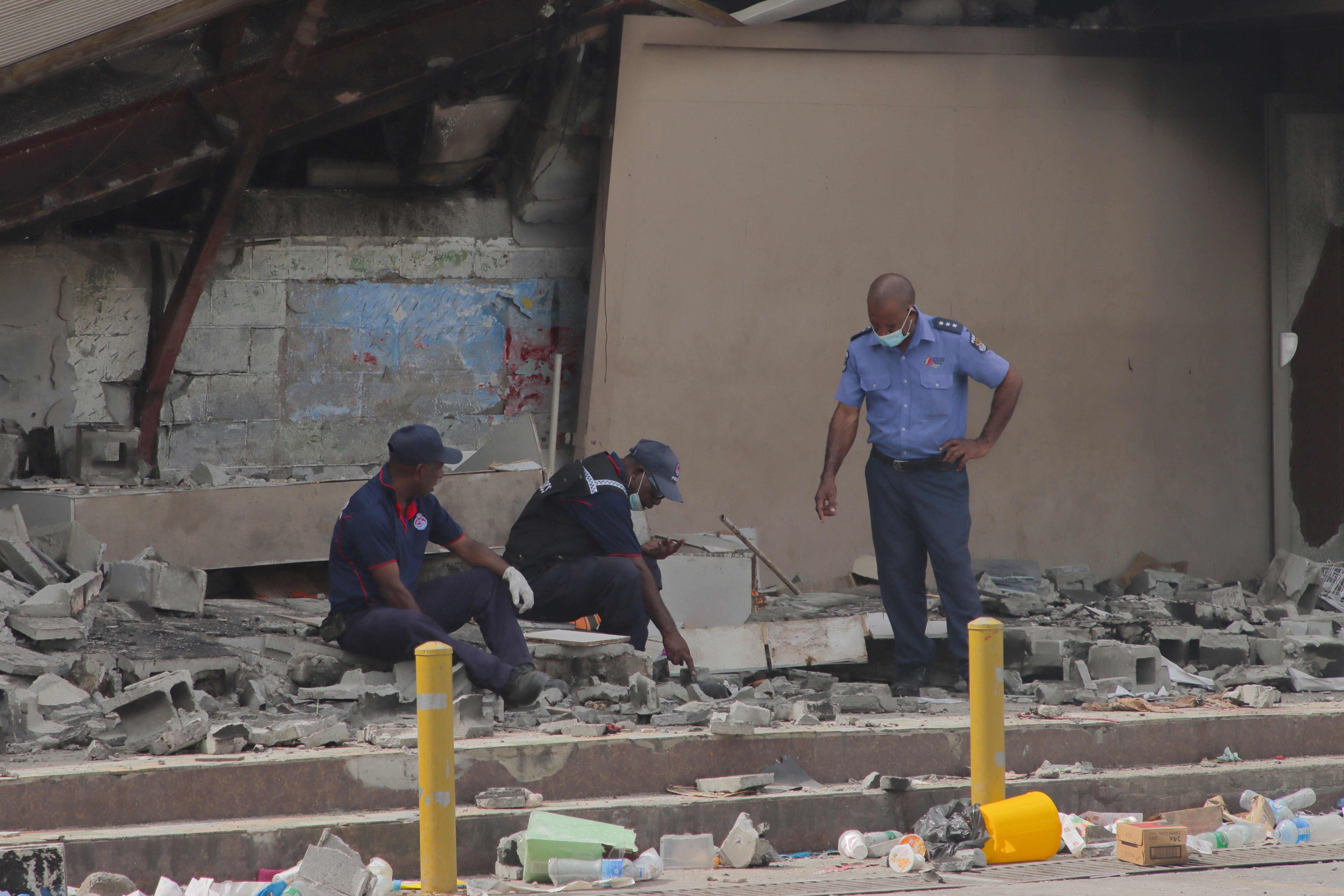 Police work at the site of a damaged building in Port Moresby on January 12. Deadly riots in Papua New Guinea laid bare the impoverished nation’s growing reliance on private security firms in place of police. Photo: AFP