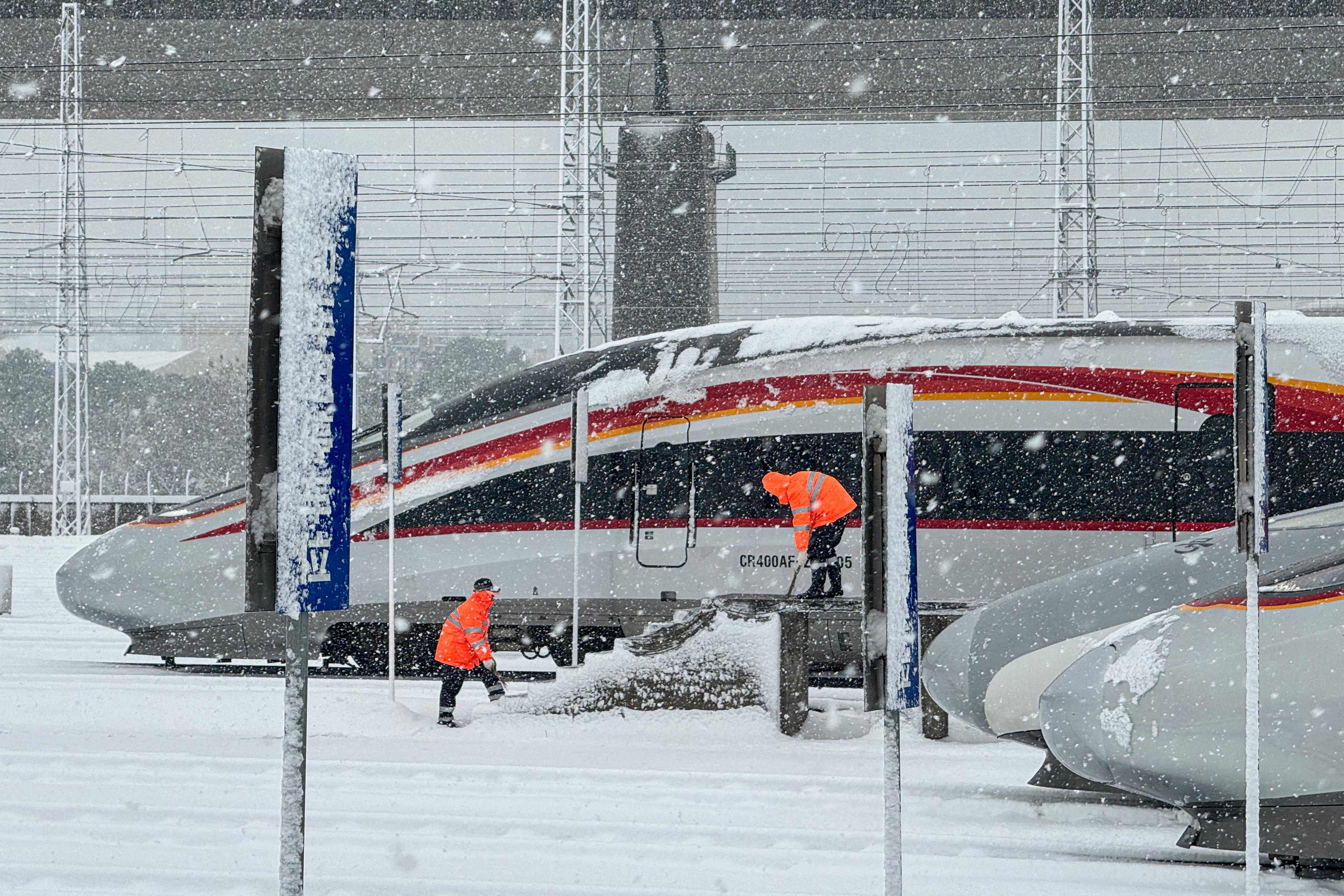 Railway workers clear snow from a bullet train in Nanchang in central China’s Jiangxi province on January 22. Chinese travellers are expected to make a record 9 billion trips during this year’s Lunar New Year holiday. Photo: AFP
