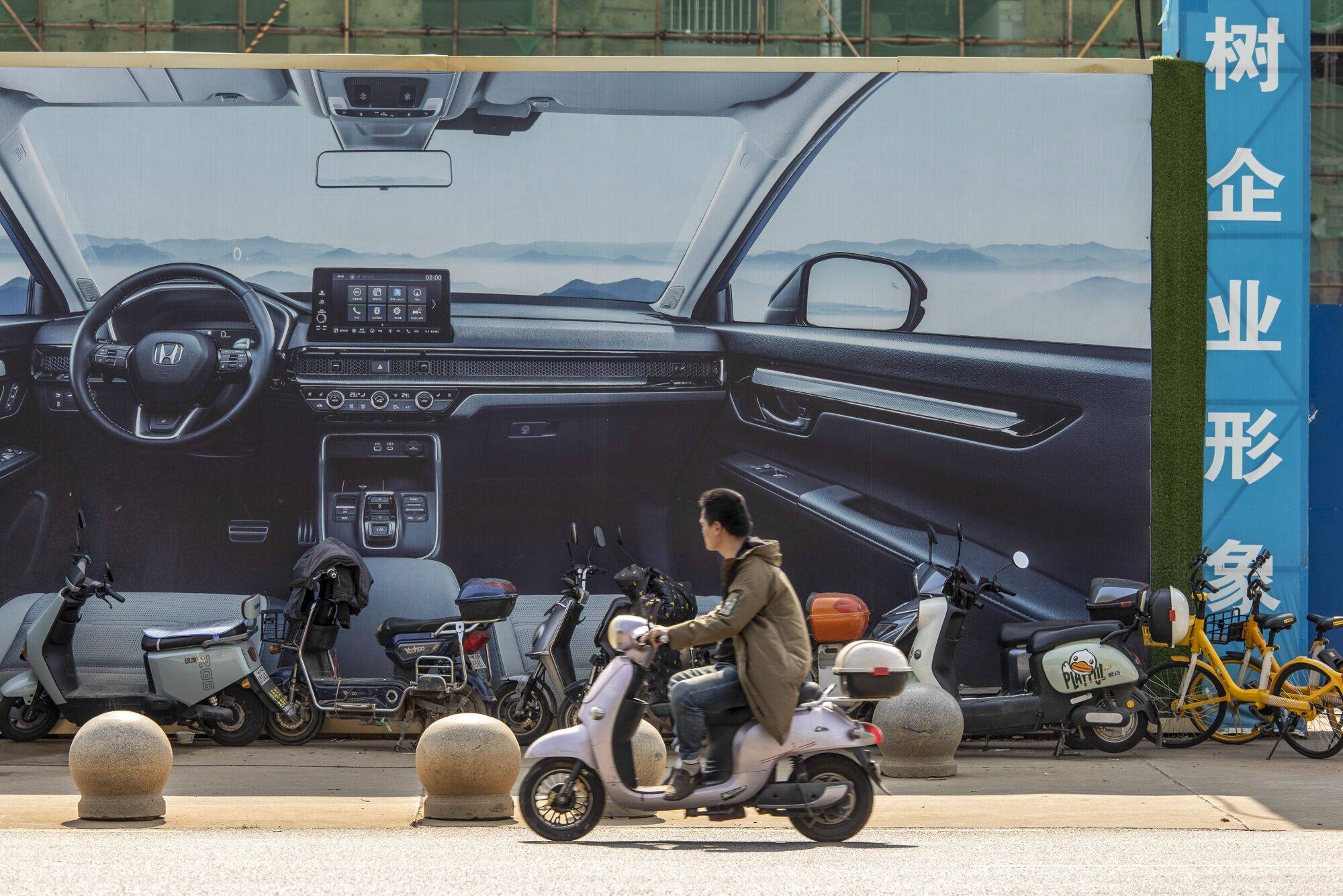 A motorcyclist passes an advertisement for electric vehicle in Wuhan, China, on October 24. Photo: Bloomberg