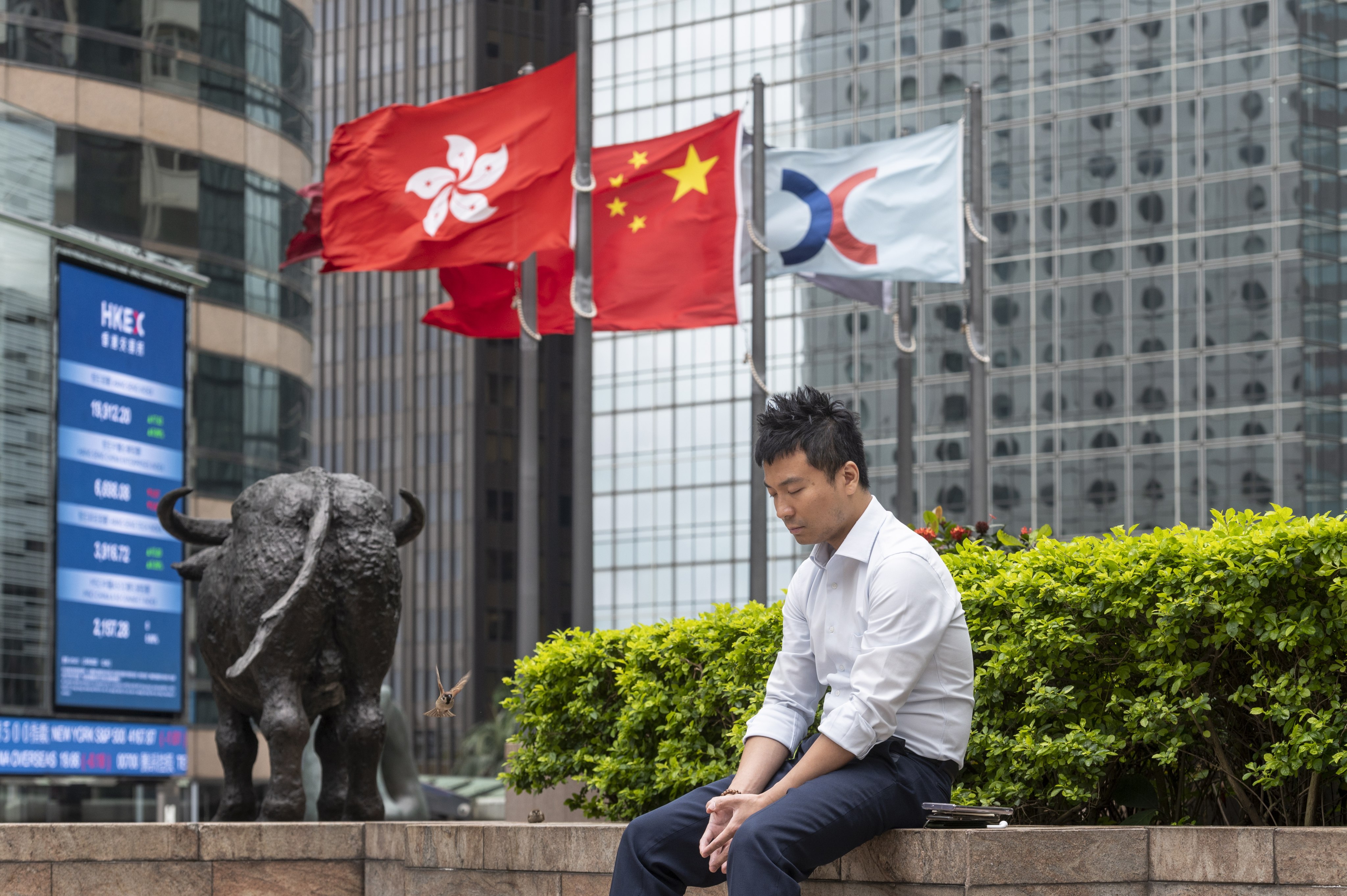 A man rests outside Exchange Square, which houses the Hong Kong stock exchange, on May 2, 2023. External shocks from two wars, US inflation and higher interest rates are taking a toll. Photo: EPA-EFE