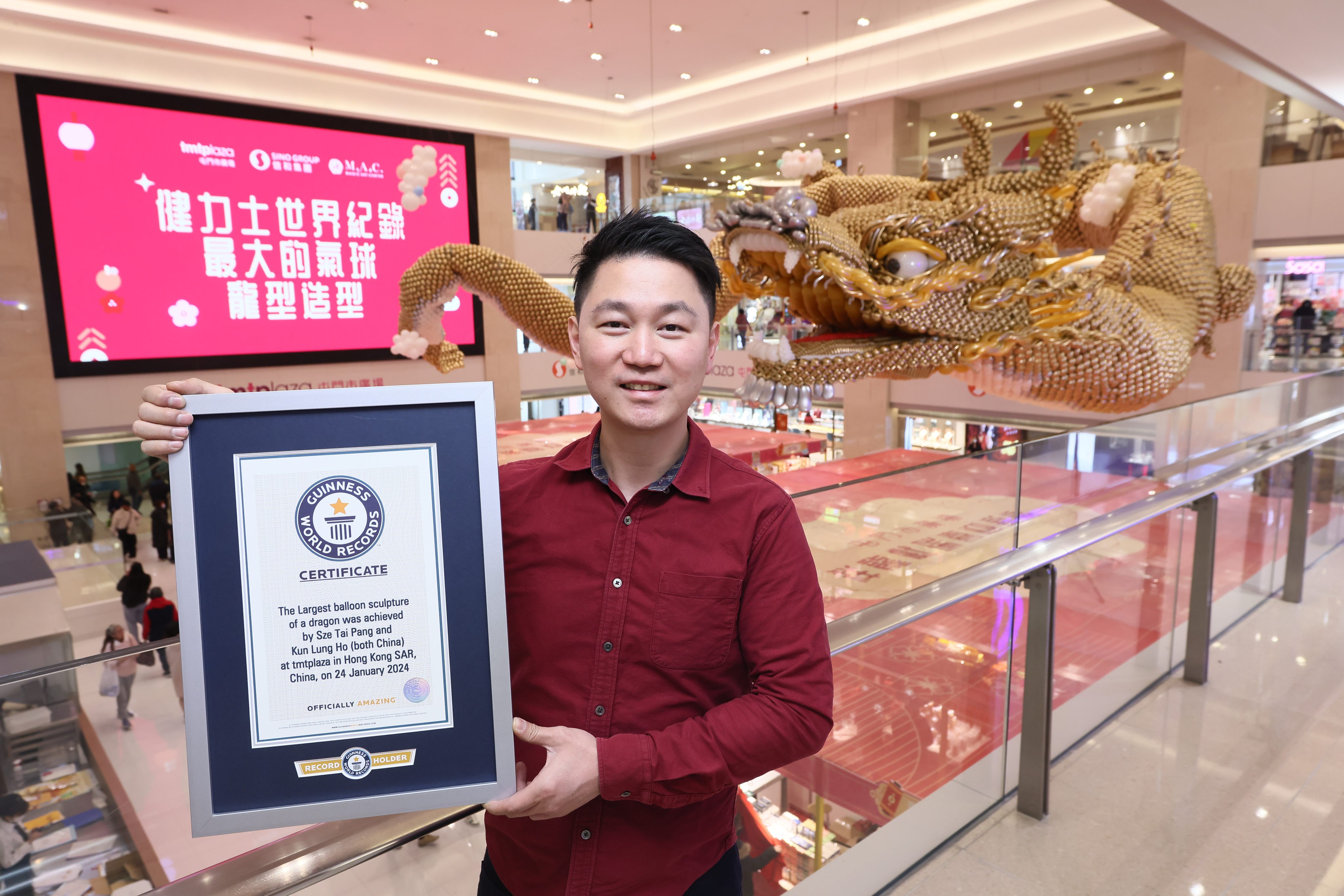 Balloon artist Wilson Pang with his 42-metre dragon sculpture - created to usher in the Year of the Dragon - and Guinness World Record certificate for the “largest balloon sculpture of a dragon” at TMTPlaza in Tuen Mun, Hong Kong. Photo: TMTPlaza