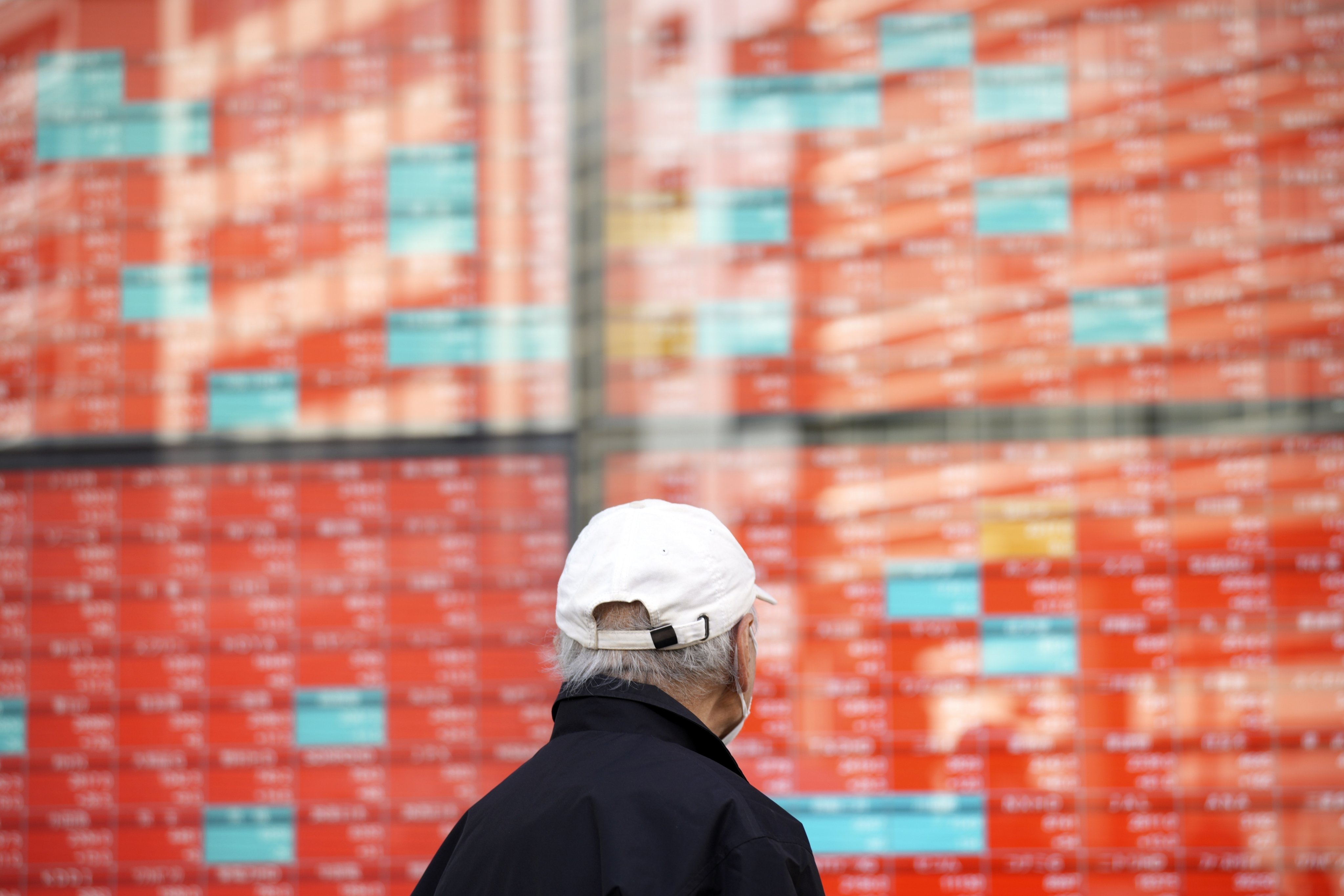 A person walks in front of an electronic stock board showing major stock indices in Tokyo on January 22, 2024. Photo: AP