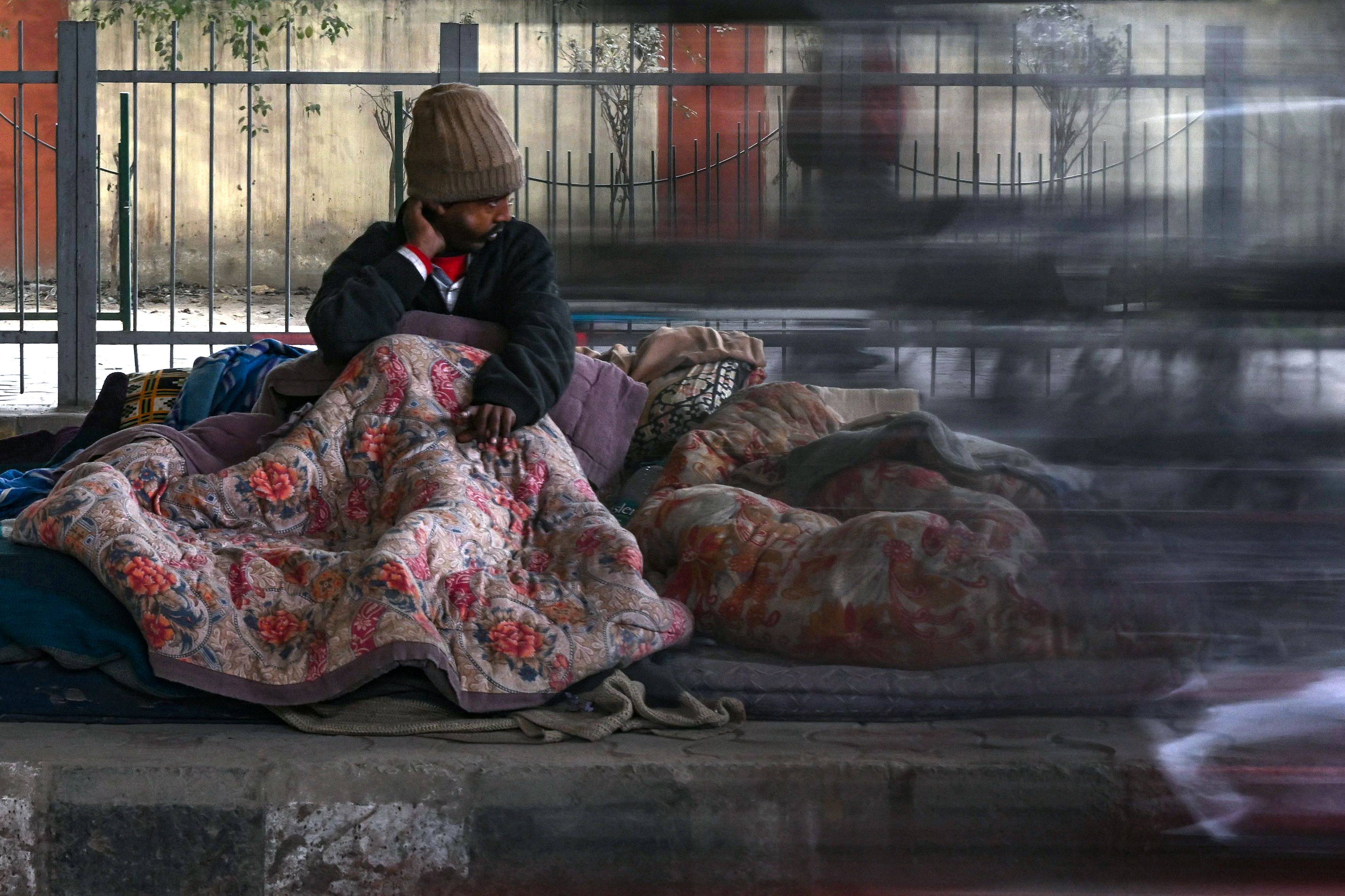 A homeless man wrapped in a quilt sits along the roadside during a cold winter morning in New Delhi, India, on January 9. Photo: AFP