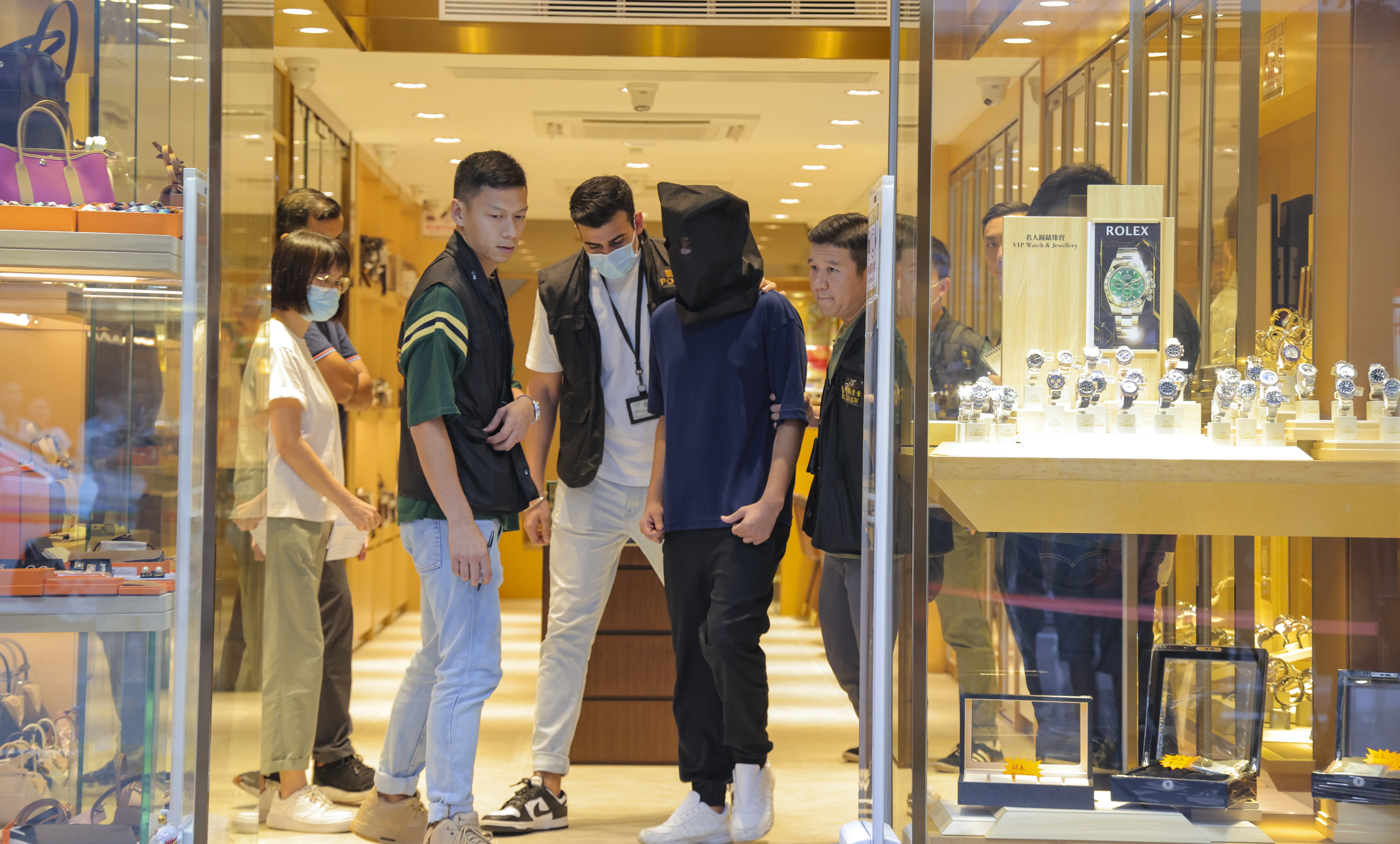 Police officers escort a suspect during a crime scene case reconstruction at a Tsim Sha Tsui watch store in September last year. Photo: Jelly Tse